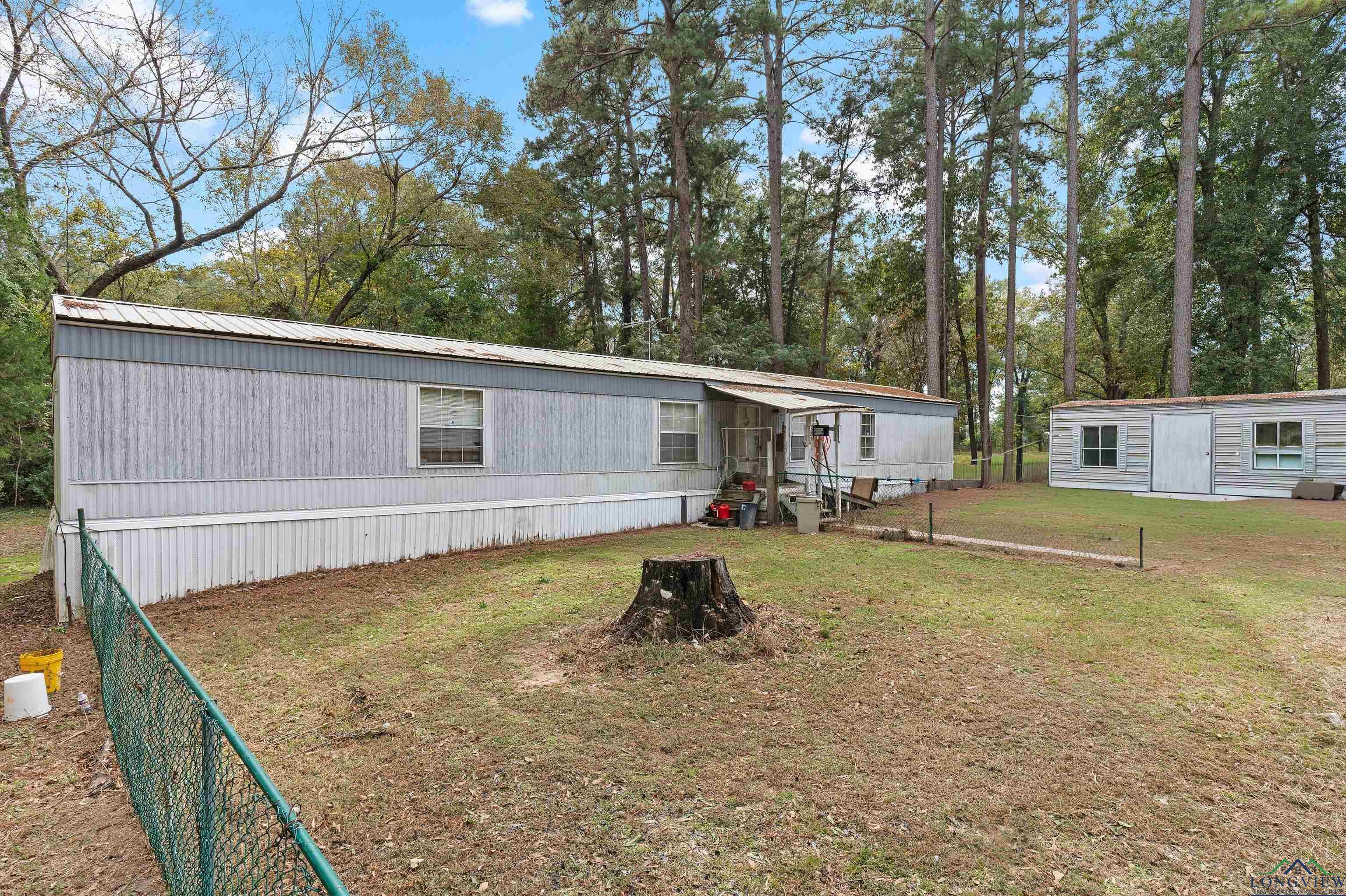 Image 0: Manufactured / mobile home with an outdoor structure, a metal roof, and view of wooded area, Front Of Structure