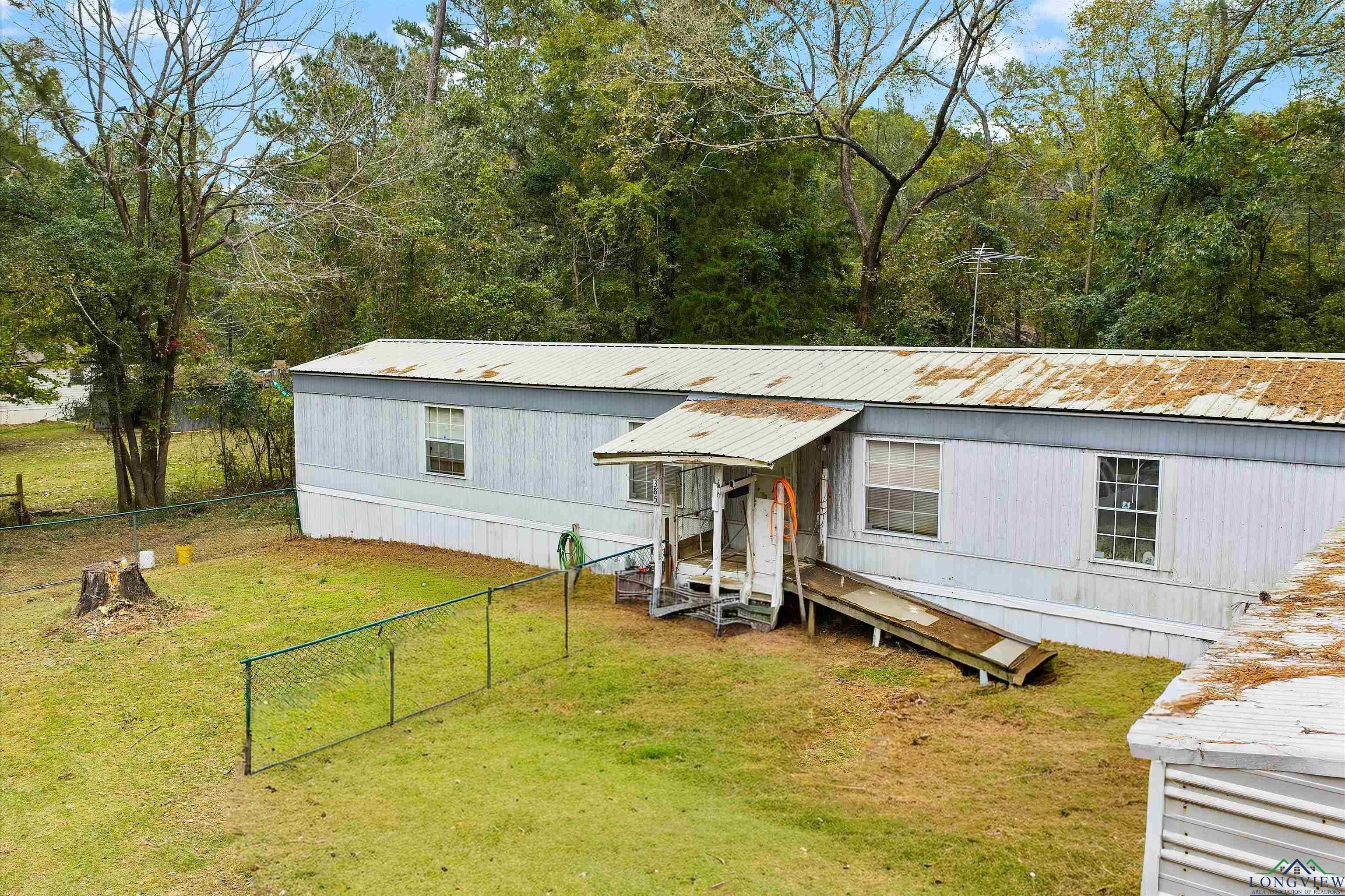 Image 1: Manufactured / mobile home featuring a fenced backyard and a metal roof, Front Of Structure