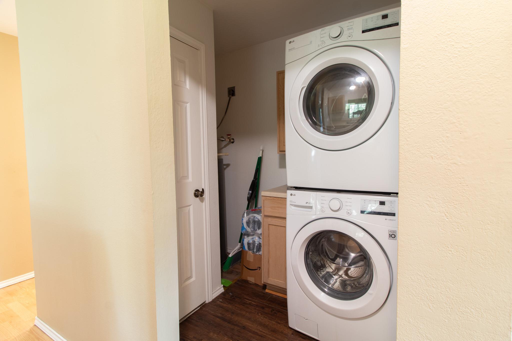 Image 3: Washroom featuring dark wood finished floors, cabinet space, and stacked washer / drying machine, Laundry