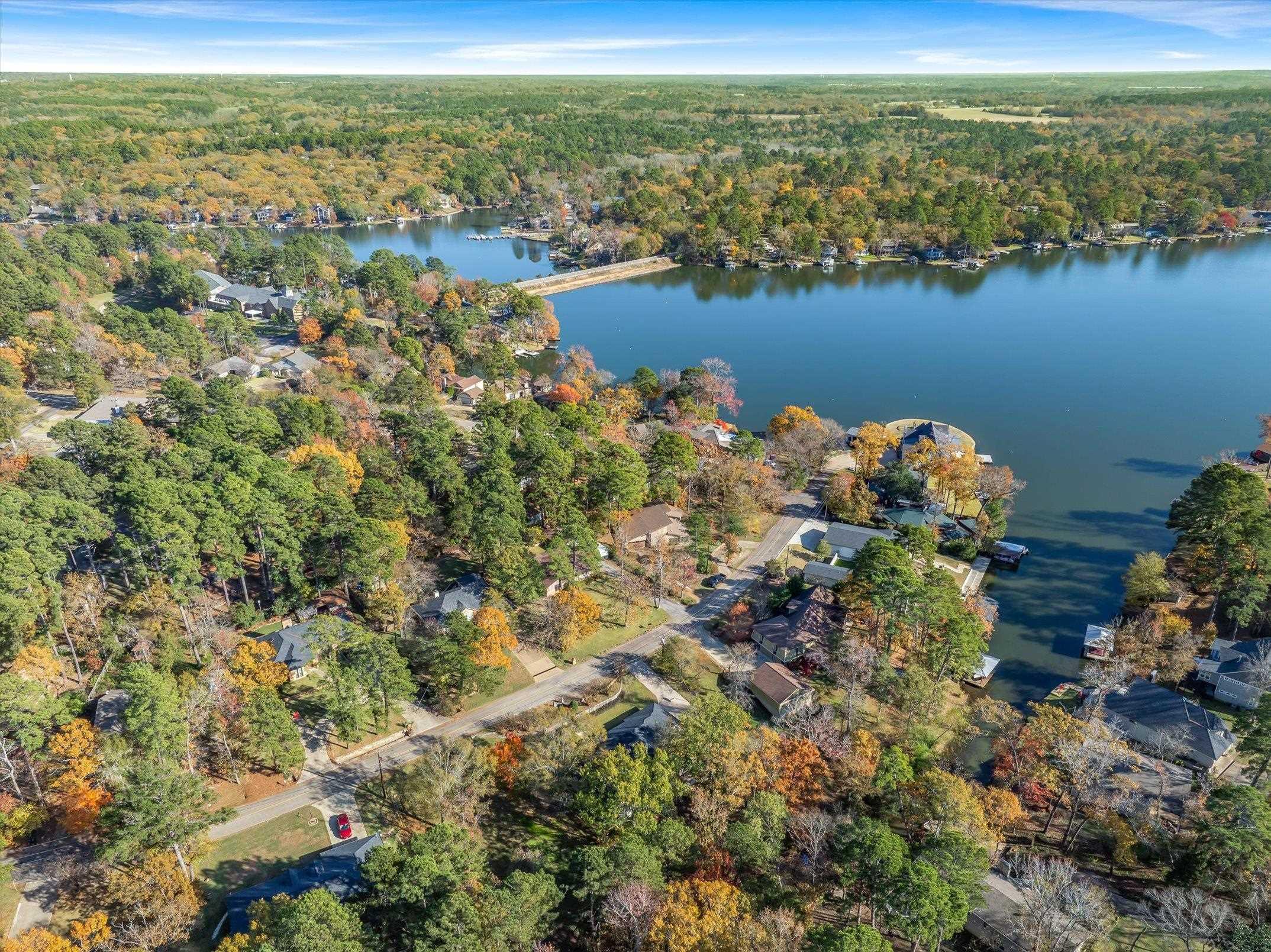 Image 2: Aerial overview of property's location featuring a heavily wooded area and a large body of water, Aerial View