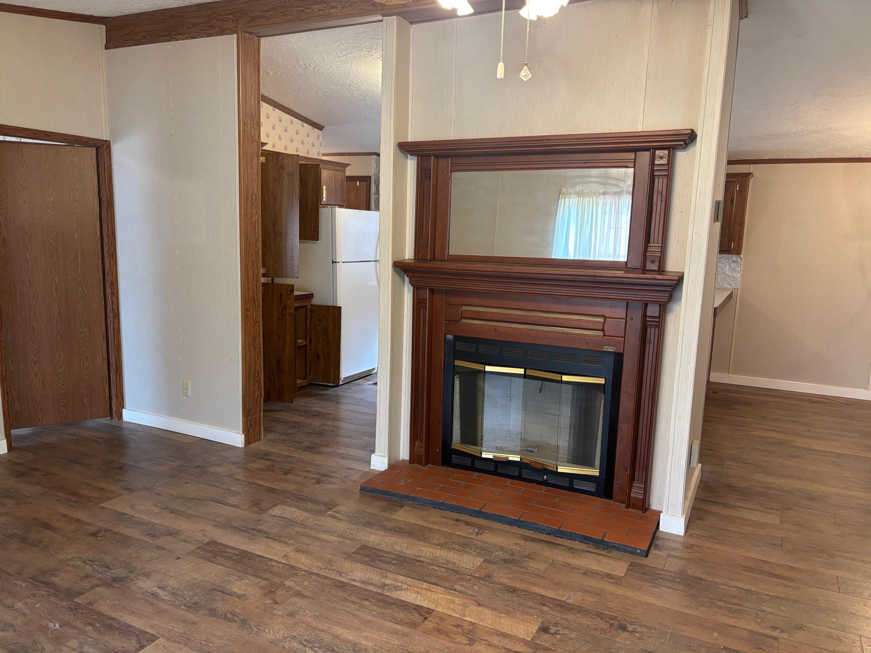 Image 2: Unfurnished living room with dark wood-style floors, a glass covered fireplace, a textured ceiling, and crown molding, Living Room