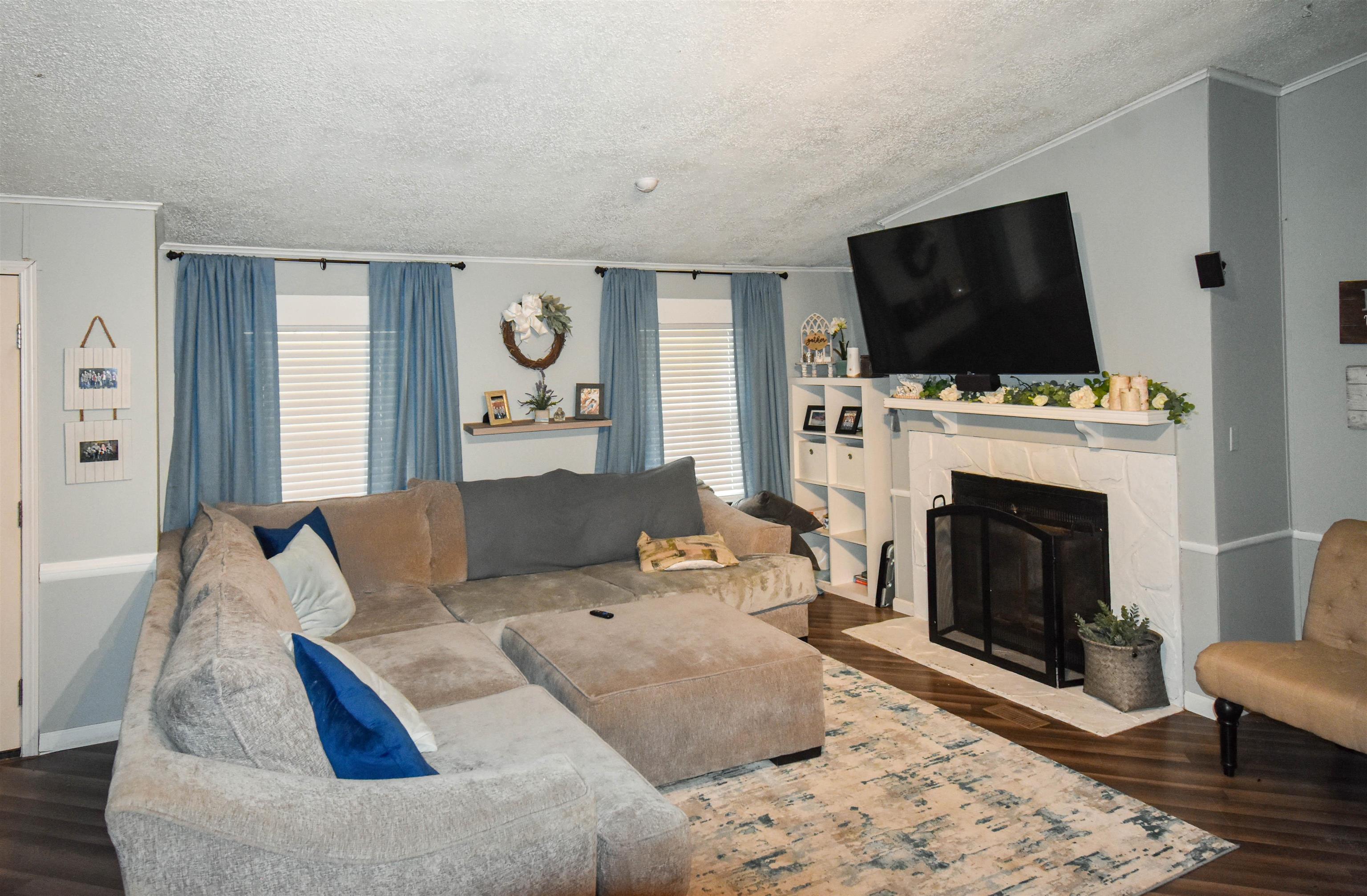 Image 3: Living room featuring dark wood finished floors, a fireplace with flush hearth, healthy amount of natural light, and ornamental molding, Living Room