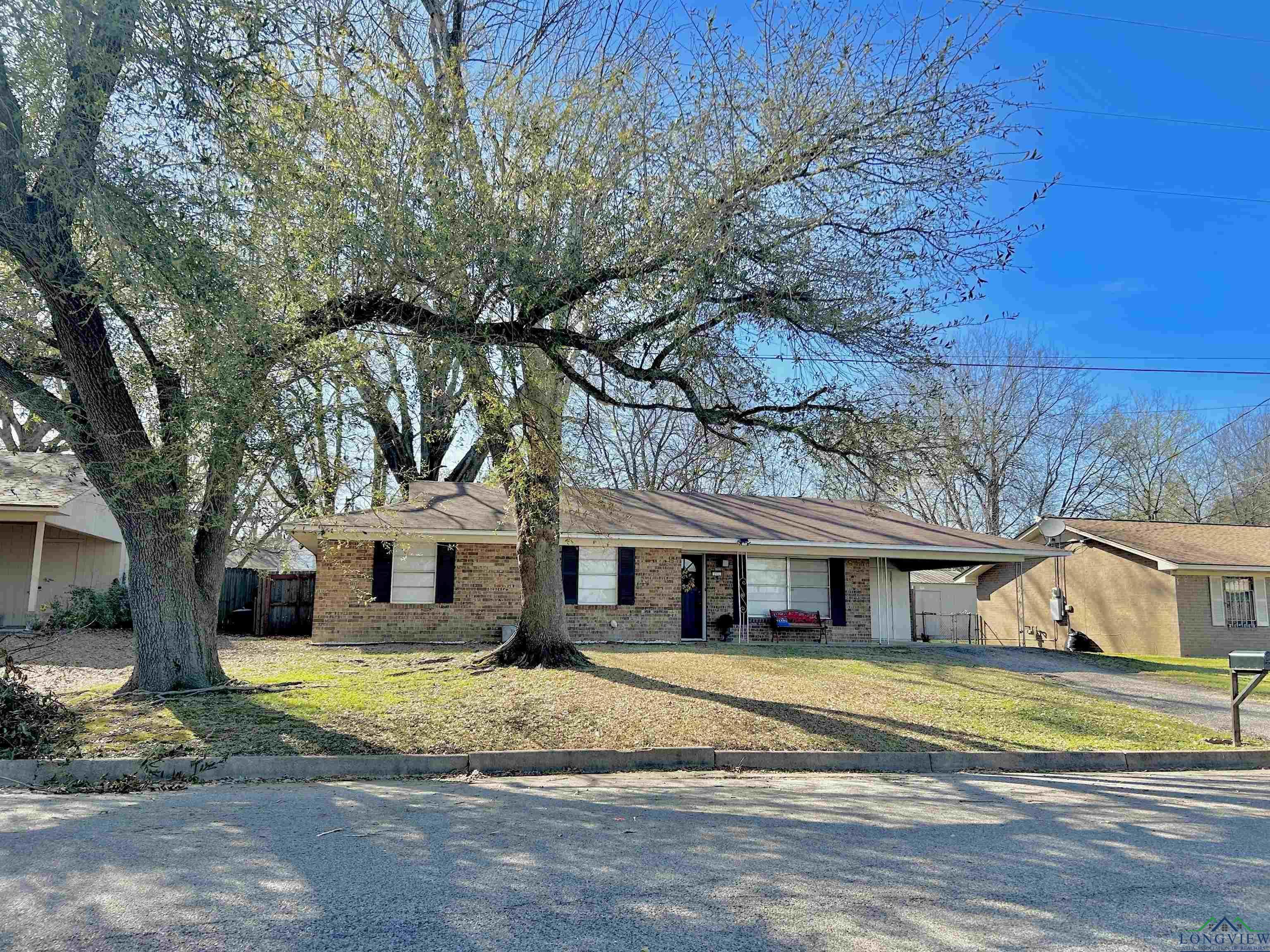 Image 2: Single story home with an attached carport, brick siding, and a front yard, Front Of Structure