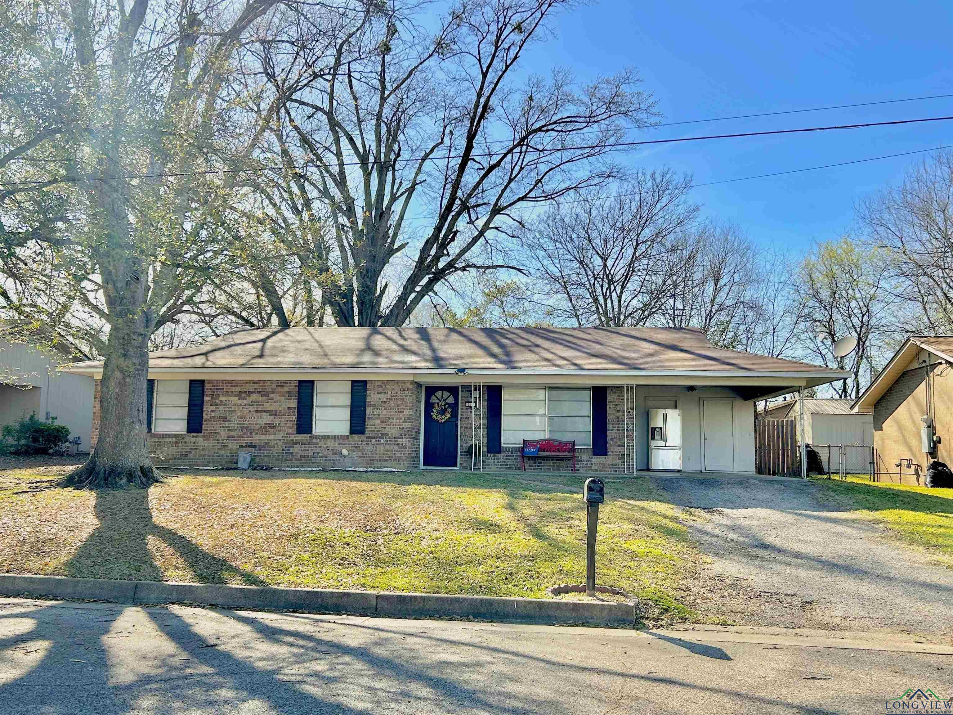 Image 3: Single story home featuring driveway, brick siding, a carport, and a front lawn, Front Of Structure