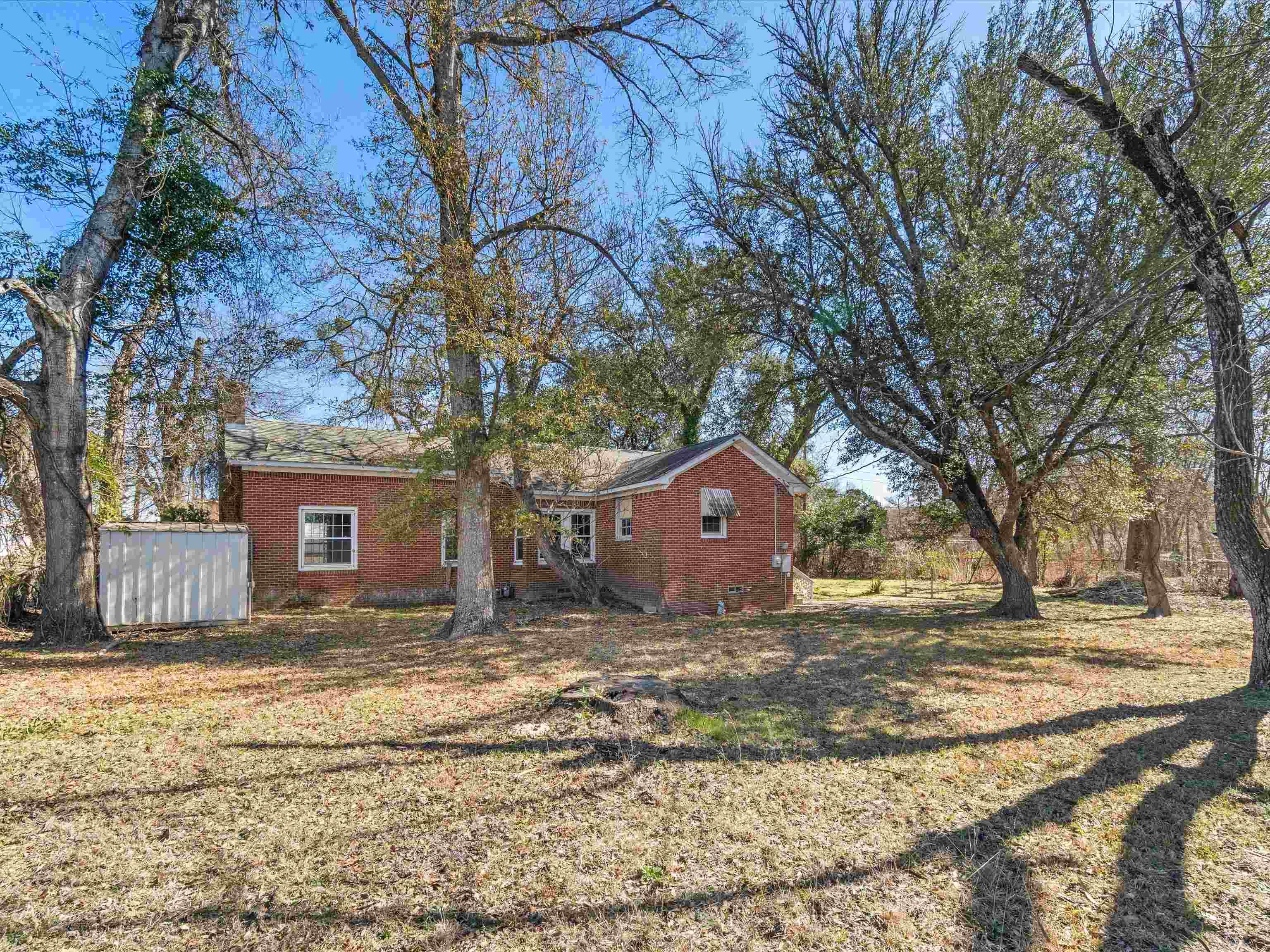 Image 1: Rear view of house featuring brick siding, a shed, and a yard, Back Of Structure