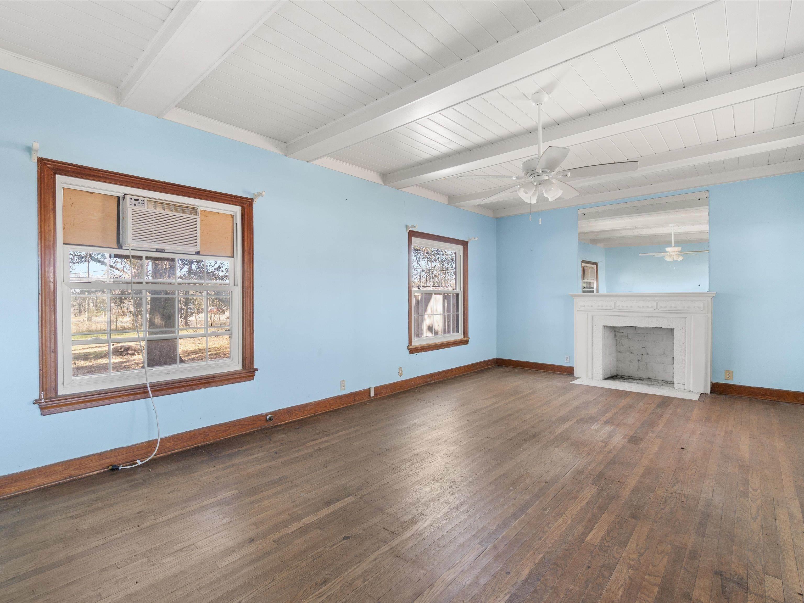 Image 3: Unfurnished living room with dark wood-style flooring, a fireplace with flush hearth, ceiling fan, and beam ceiling, Living Room