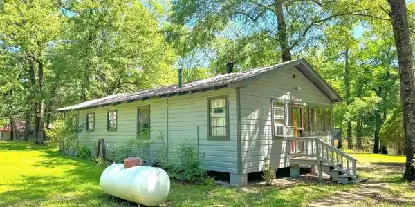 Image 1: View of home's exterior with a yard and view of scattered trees, Side Of Structure