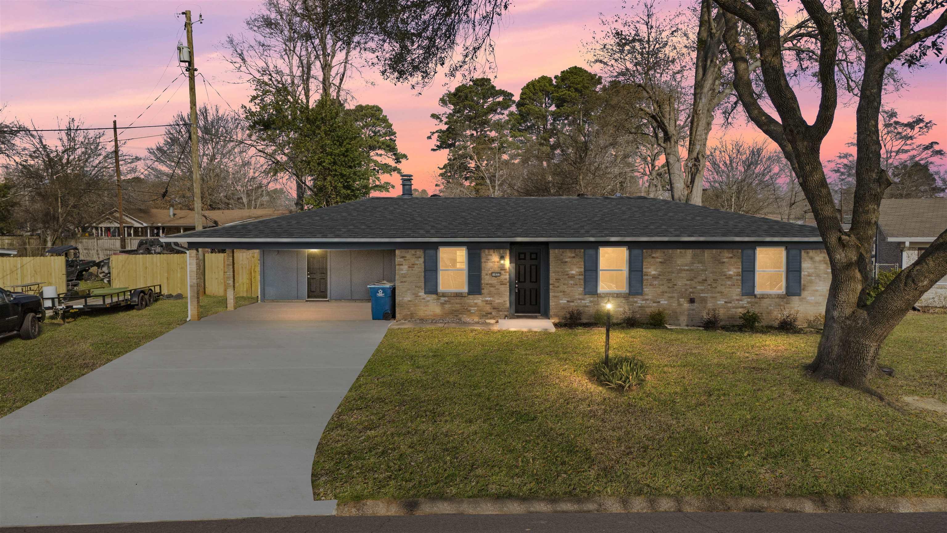 Image 0: Ranch-style house with a shingled roof, driveway, brick siding, and a carport, Front Of Structure