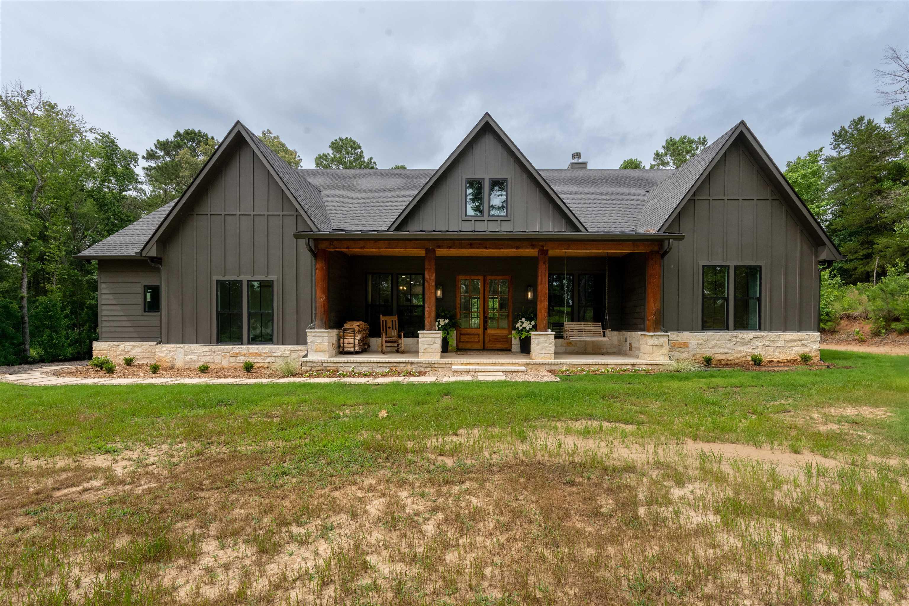 Image 0: Contemporary farmhouse exterior featuring dark gray board and batten siding, Back Of Structure
