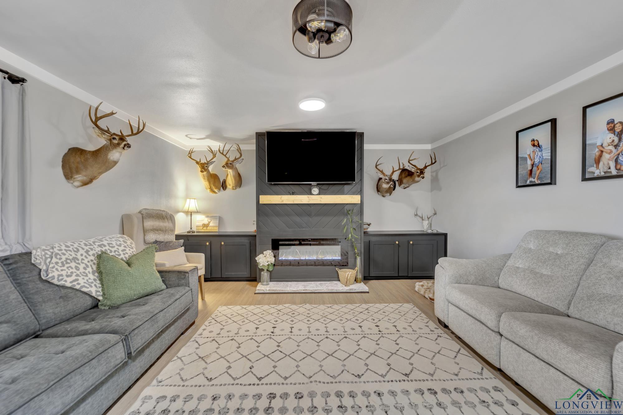Image 4: Living area with ornamental molding, light wood-style floors, and a fireplace, Living Room