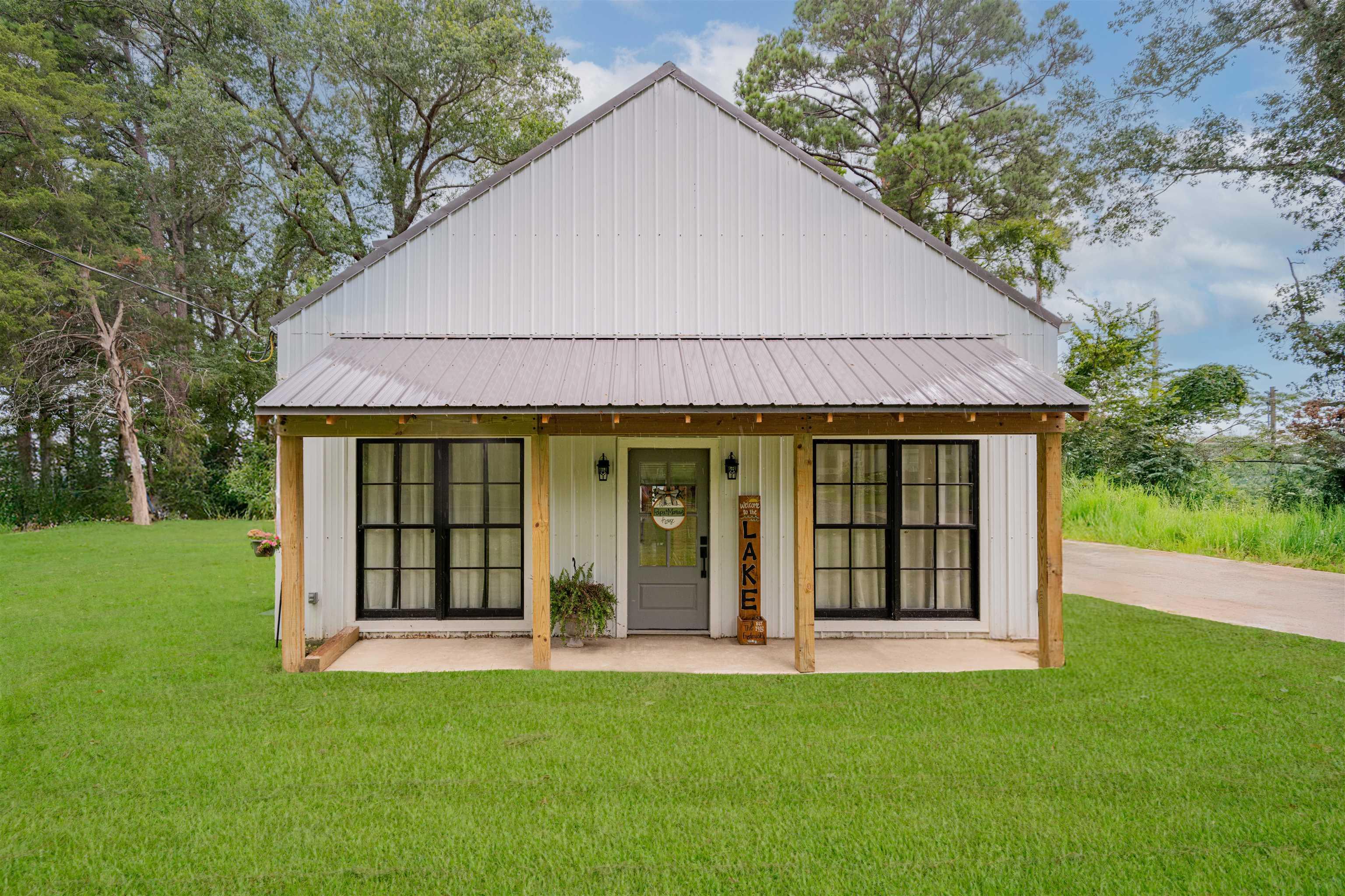 Image 1: View of front of house with a front yard, a metal roof, and board and batten siding, Front Of Structure