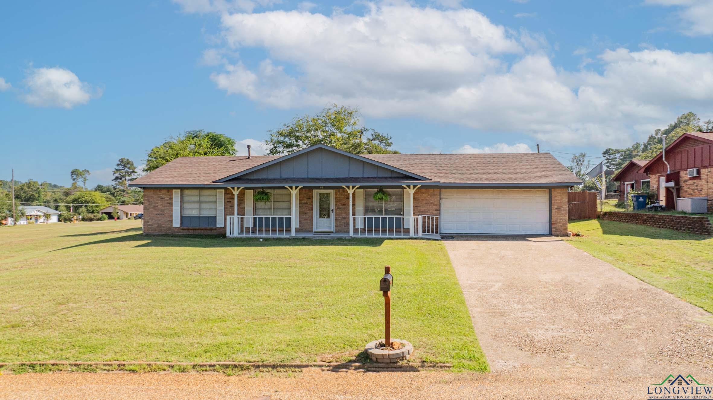 Image 1: Single story home with covered porch, brick siding, and a front lawn, Front Of Structure