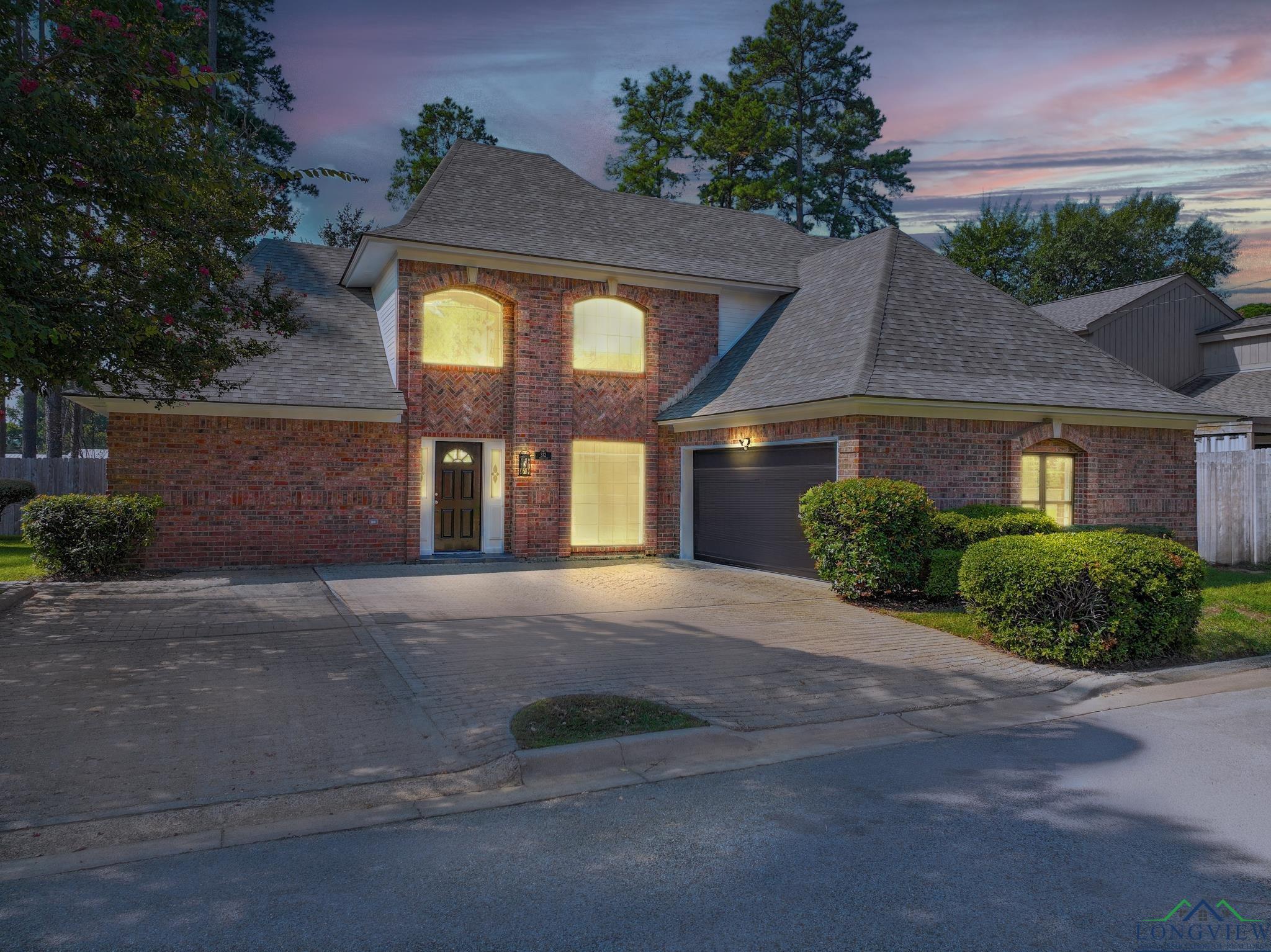 Image 0: Traditional-style home with a shingled roof, driveway, brick siding, and a garage, Front Of Structure