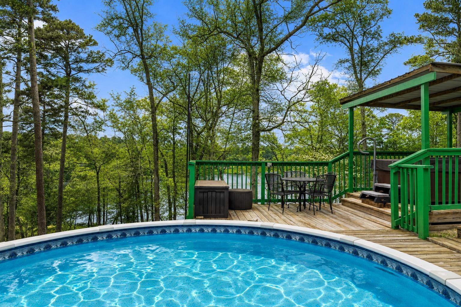 Image 1: Outdoor oasis featuring an above-ground swimming pool, expansive wood deck, and covered hot tub area, Pool