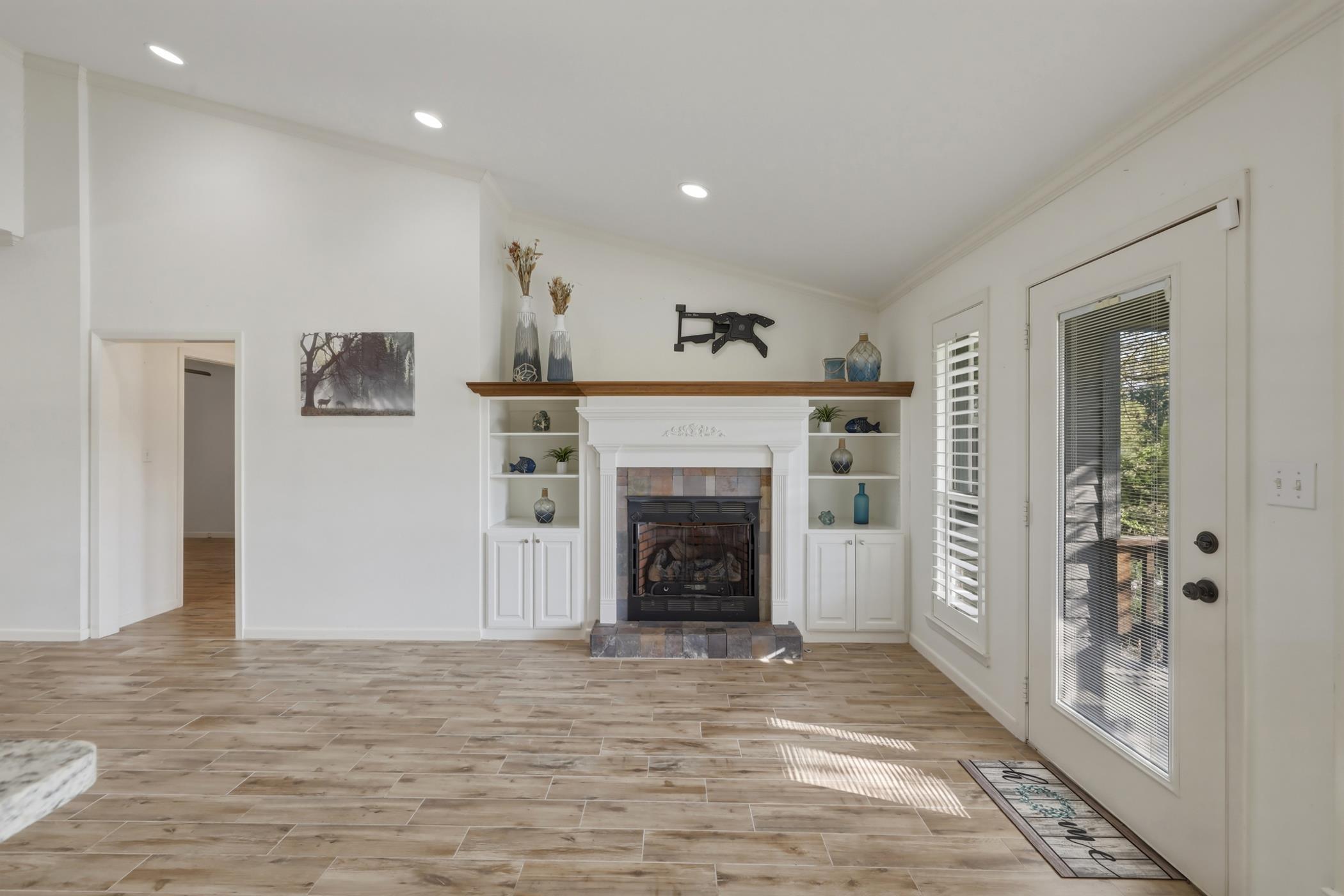 Image 1: Unfurnished living room with vaulted ceiling, wood tiled floors, a fireplace, and recessed lighting, Living Room