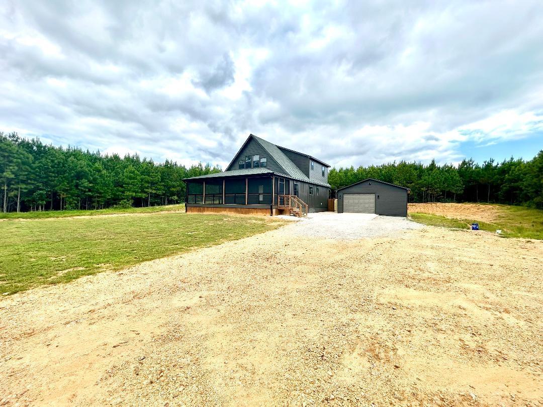 Image 1: View of front of home with a sunroom, an outdoor structure, driveway, a garage, and a front lawn
