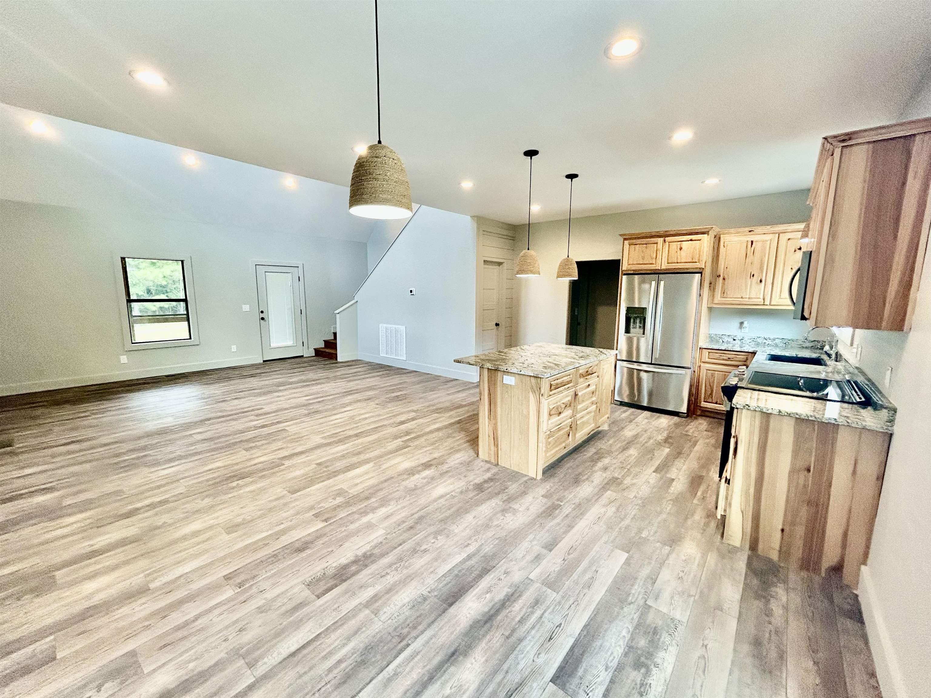 Image 2: Kitchen featuring a kitchen island, stainless steel fridge, light wood finished floors, hanging light fixtures, and recessed lighting