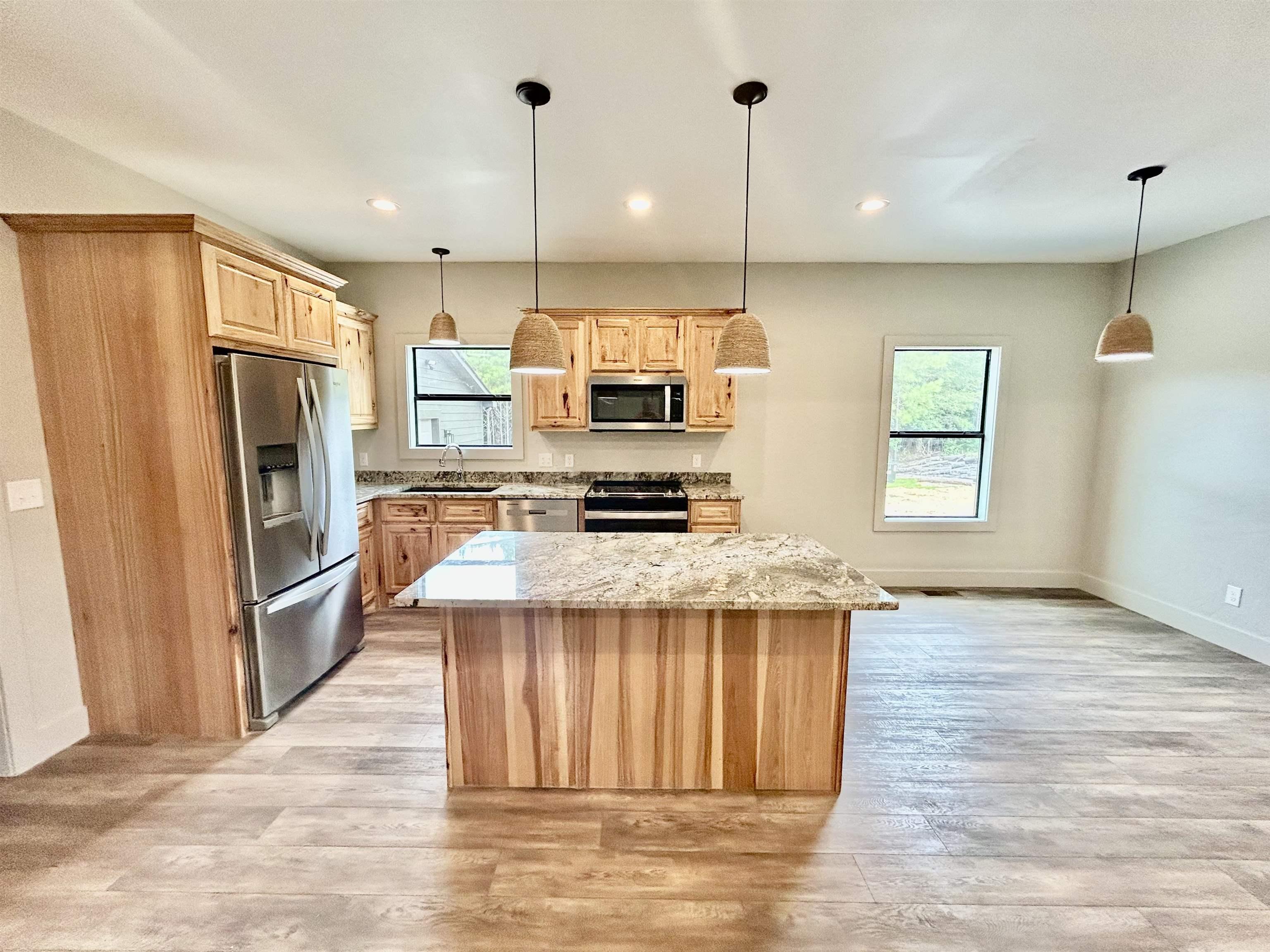 Image 4: Kitchen with light brown cabinets, appliances with stainless steel finishes, light wood-style flooring, a center island, and recessed lighting