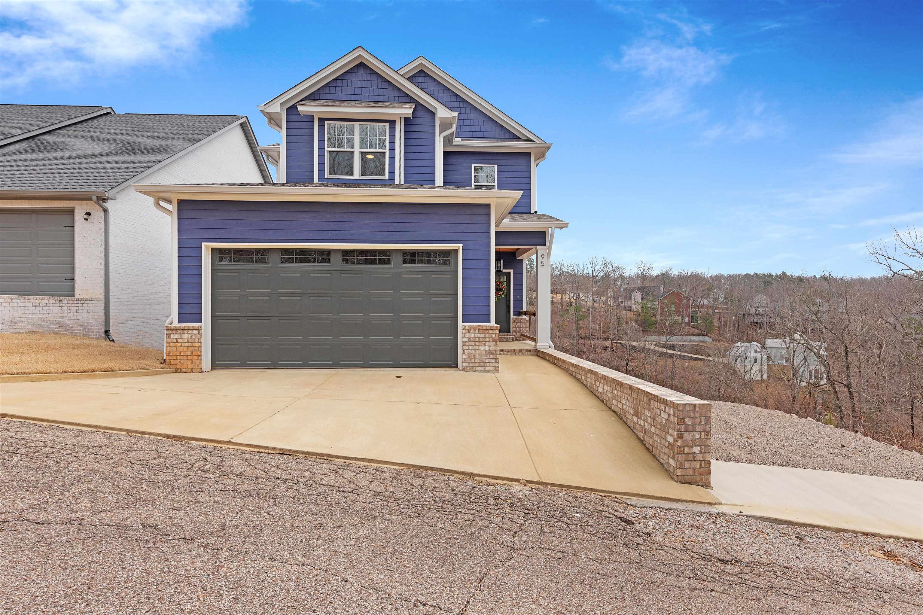 Image 2: View of front of house with driveway, a garage, a porch, and brick siding