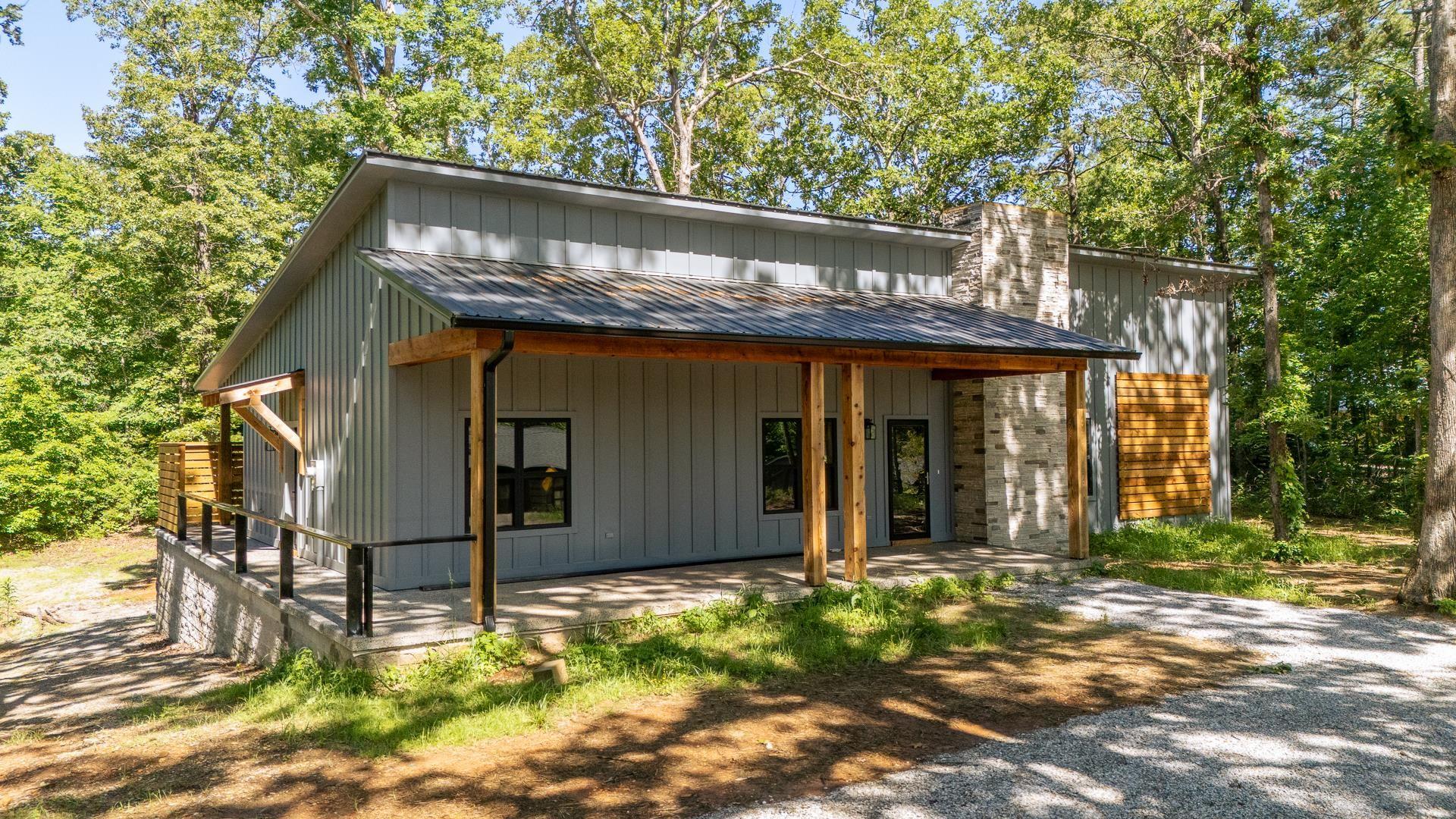 Image 1: View of front of home with a metal roof, a porch, board and batten siding, and a chimney