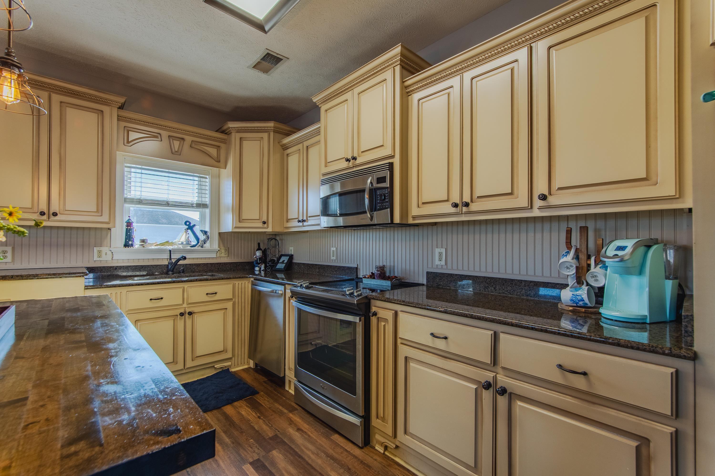 Image 4: Kitchen with appliances with stainless steel finishes, dark stone counters, dark wood-type flooring, sink, and pendant lighting