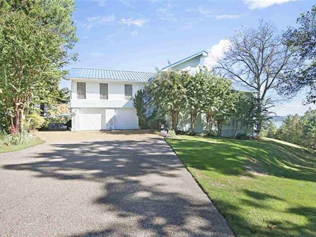 Image 3: View of front of property with driveway, an attached garage, a metal roof, a front lawn, and stucco siding