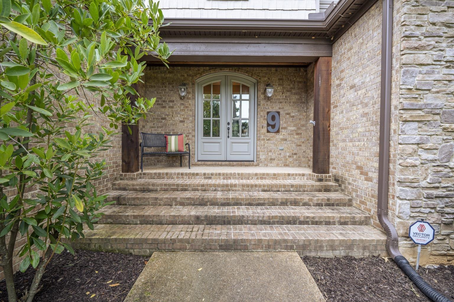 Image 2: Foyer entrance featuring a light-colored double door, brick facade, stone veneer accents, and recessed outdoor lighting