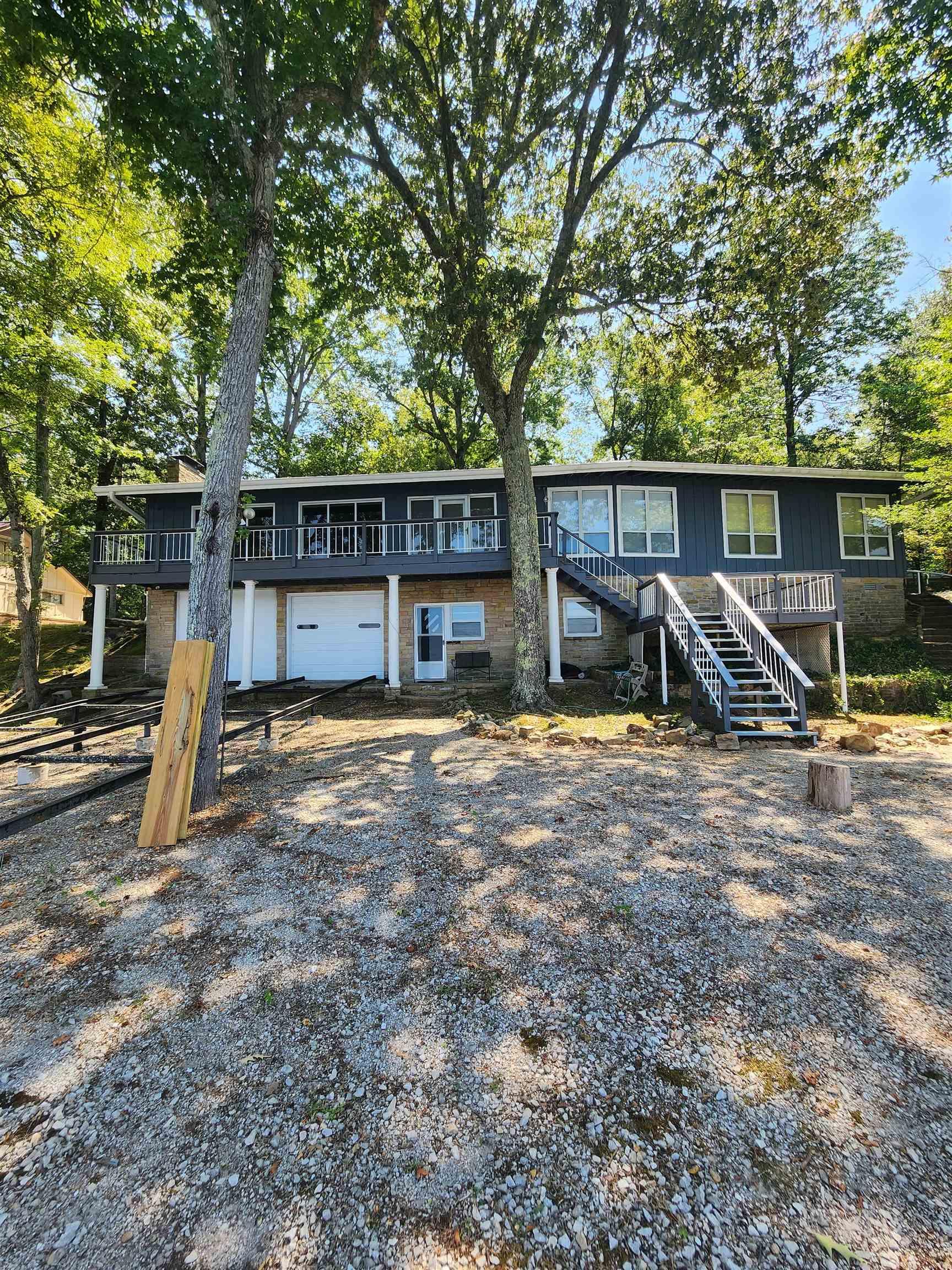 Image 4: View of front of property featuring stairs, a garage, a deck, and driveway