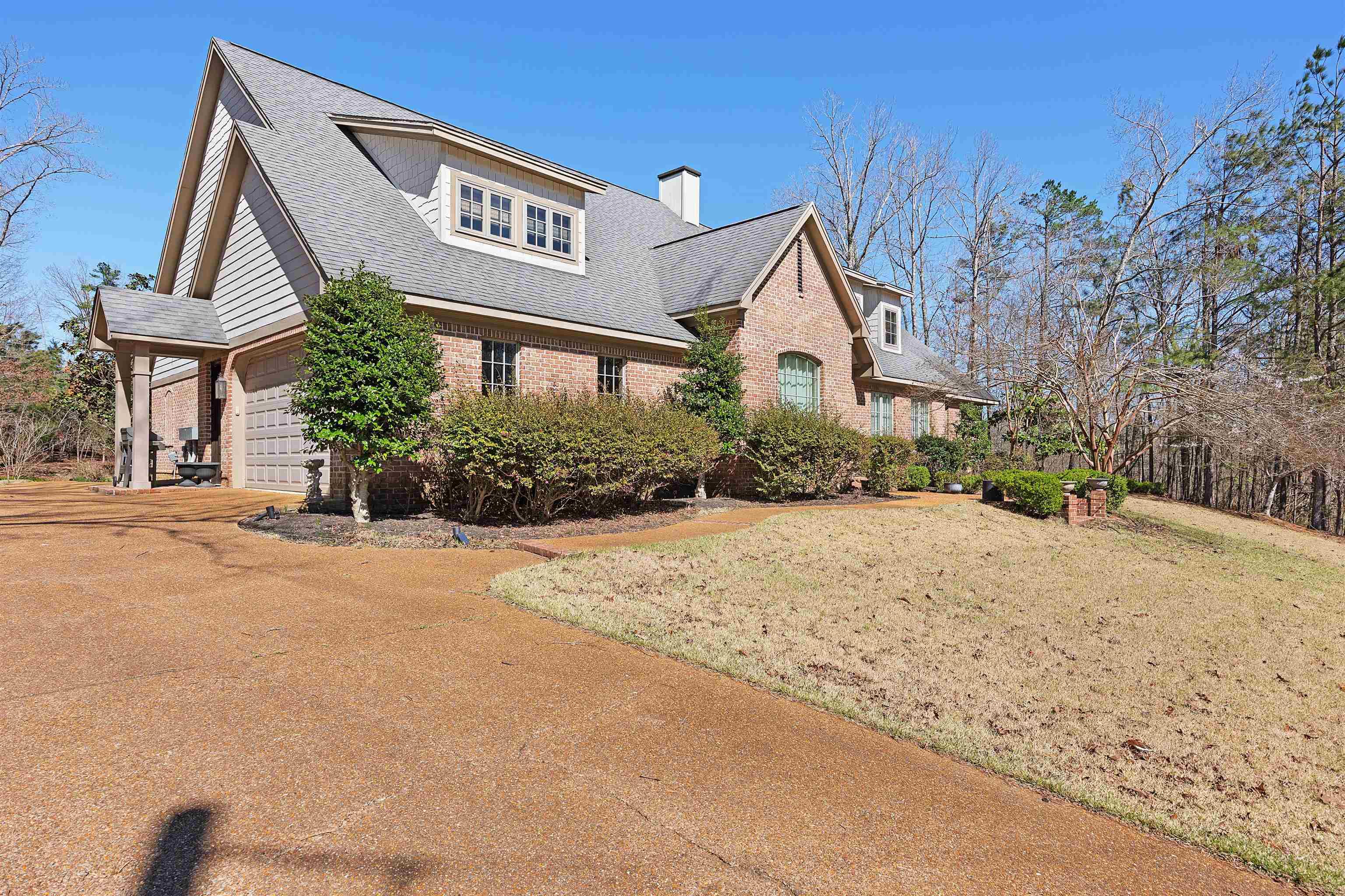 Image 3: View of front of house with brick siding, a front yard, a shingled roof, a chimney, and driveway