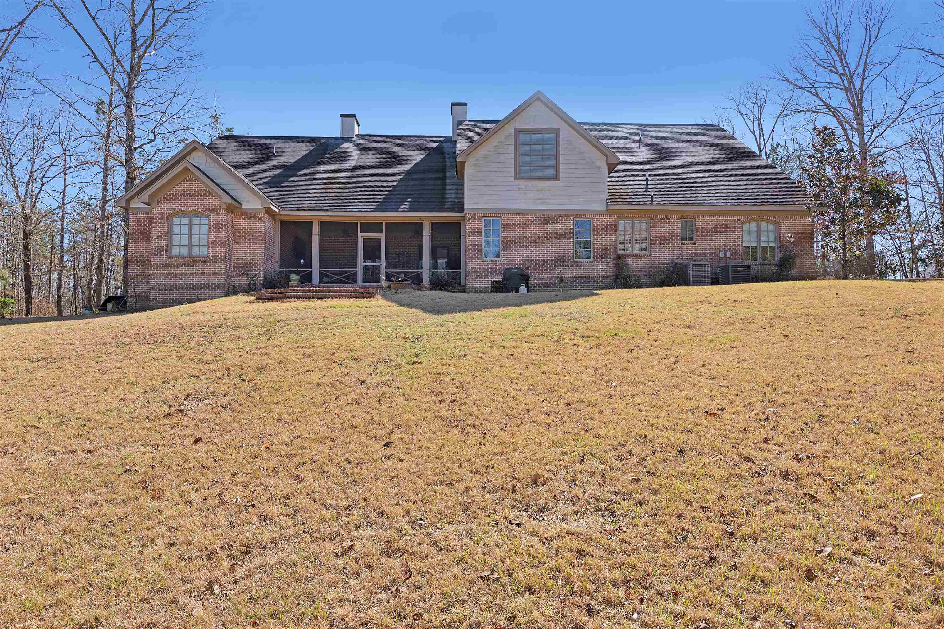 Image 4: Back of house with a chimney, a sunroom, a yard, brick siding, and a shingled roof