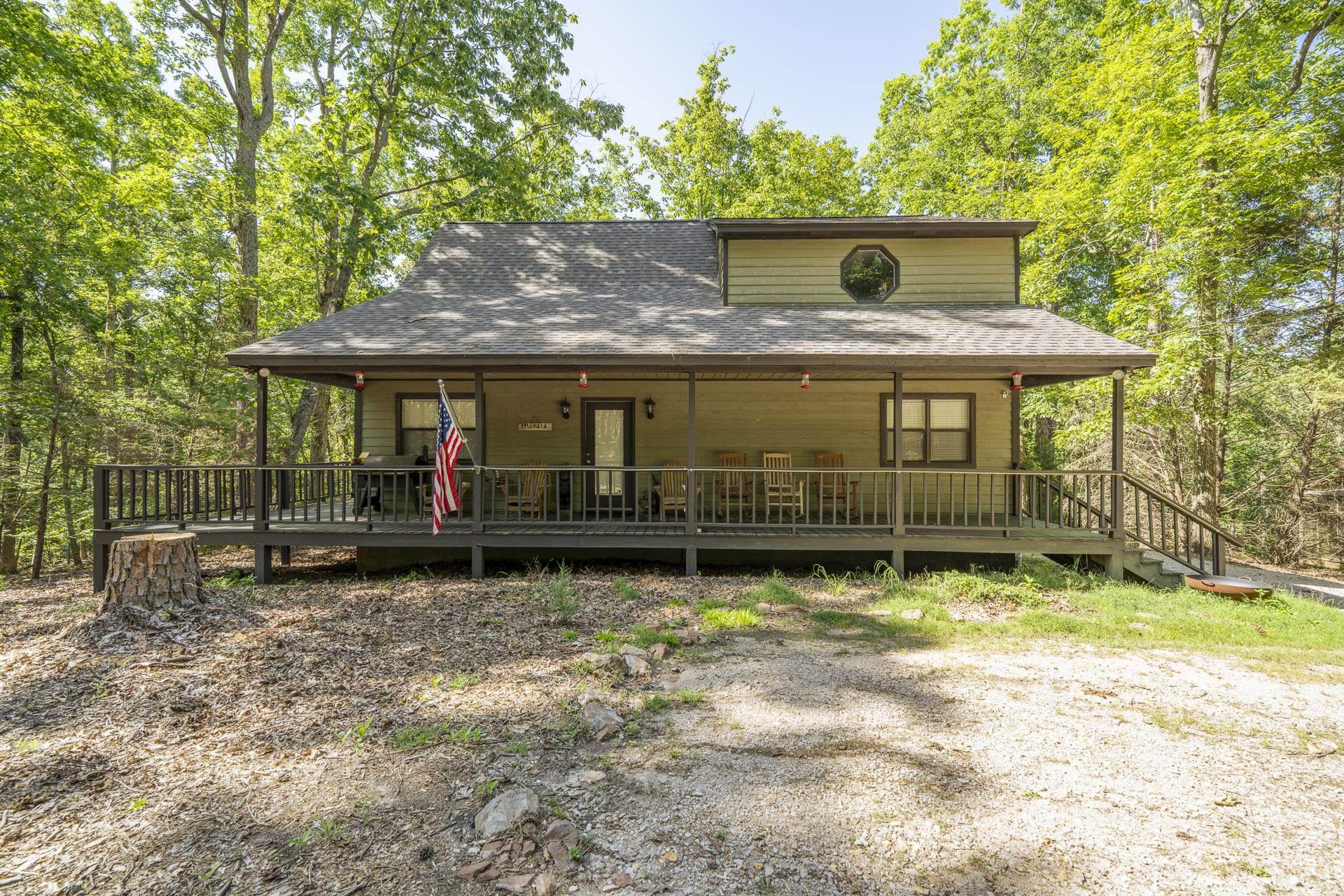 Image 1: Wooded property featuring a covered front porch with dark railings and support posts