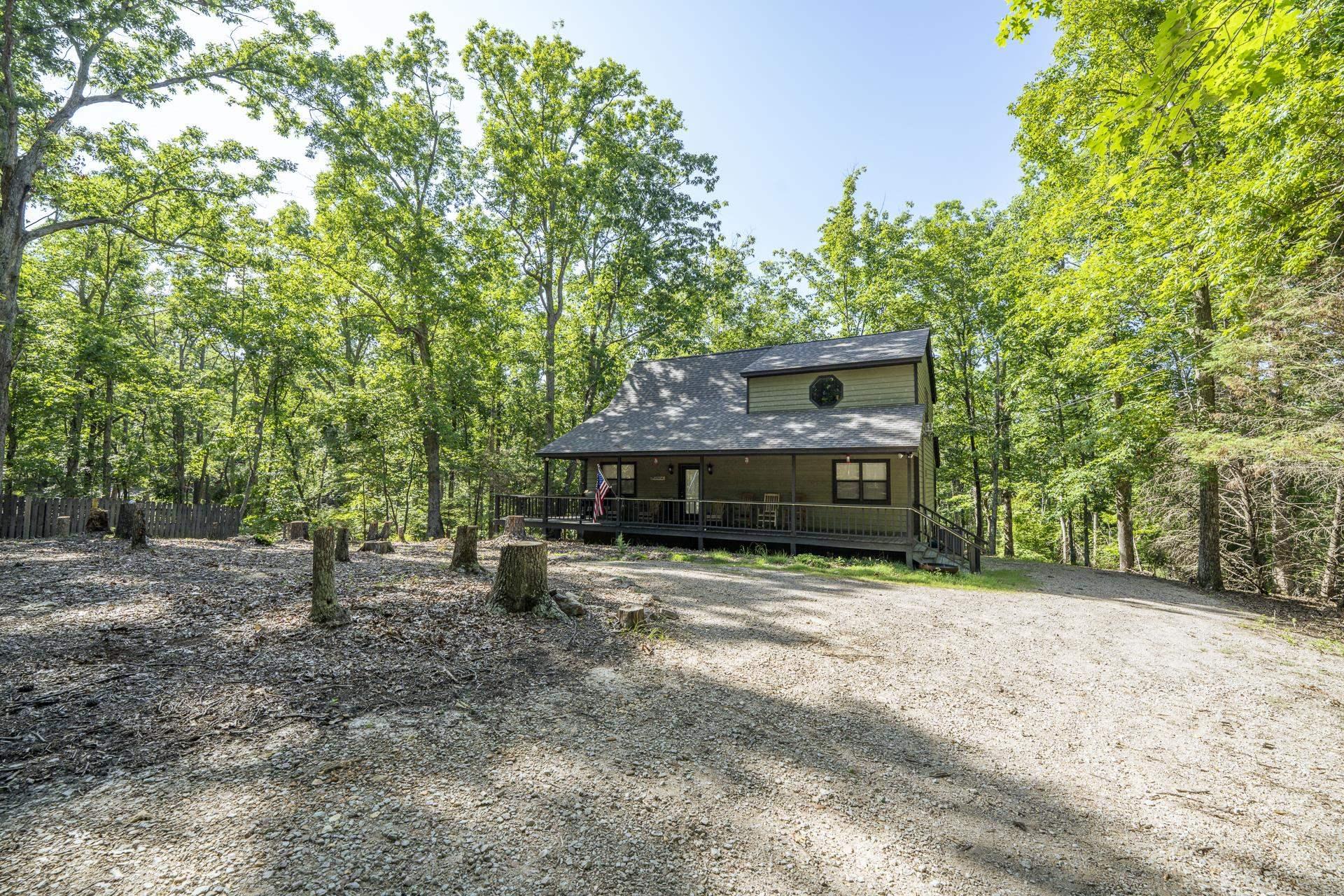 Image 2: Wooded lot featuring a two-story home with a covered front porch, dark siding, and a circular window accent