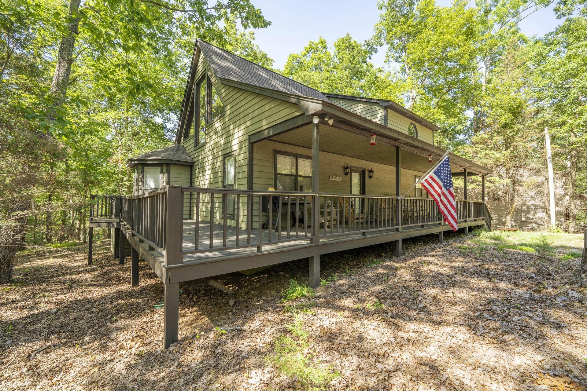 Image 4: Wood-sided residence featuring a covered front porch and expansive wrap-around deck