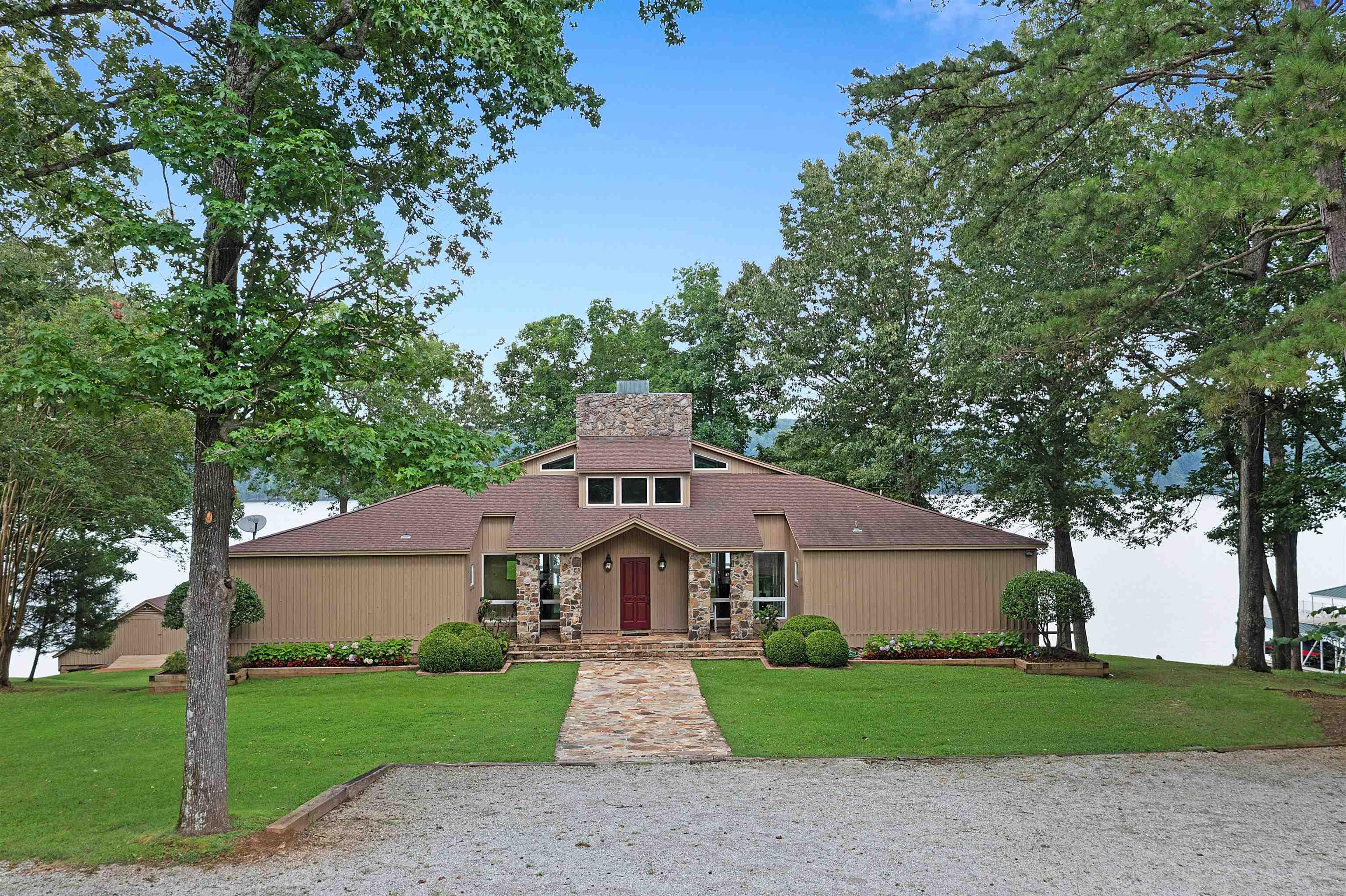 Image 1: Mid-century home featuring a chimney, a front lawn, and stone siding