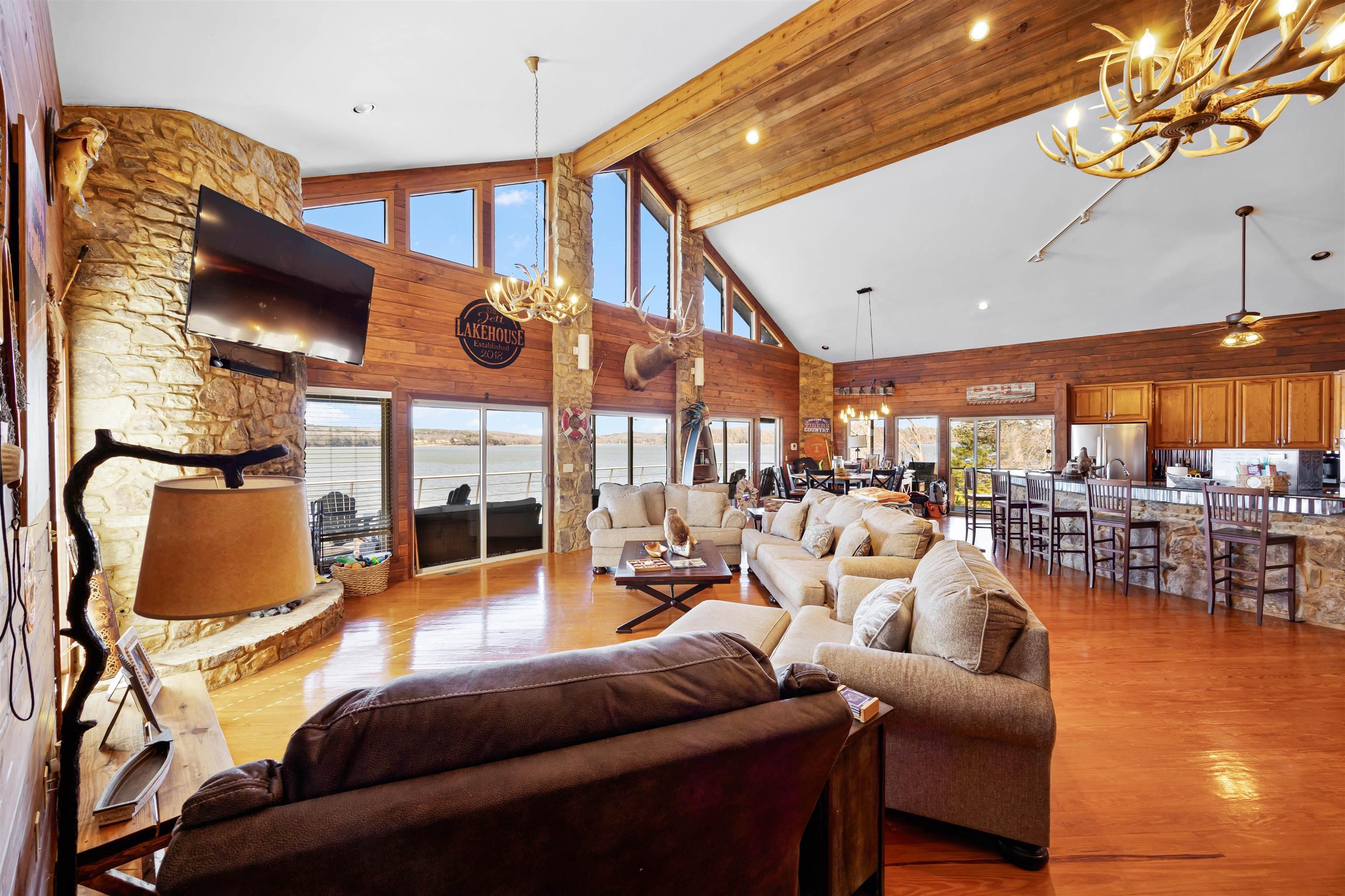 Image 4: Living room with ceiling fan with notable chandelier, high vaulted ceiling, wood finished floors, and beamed ceiling