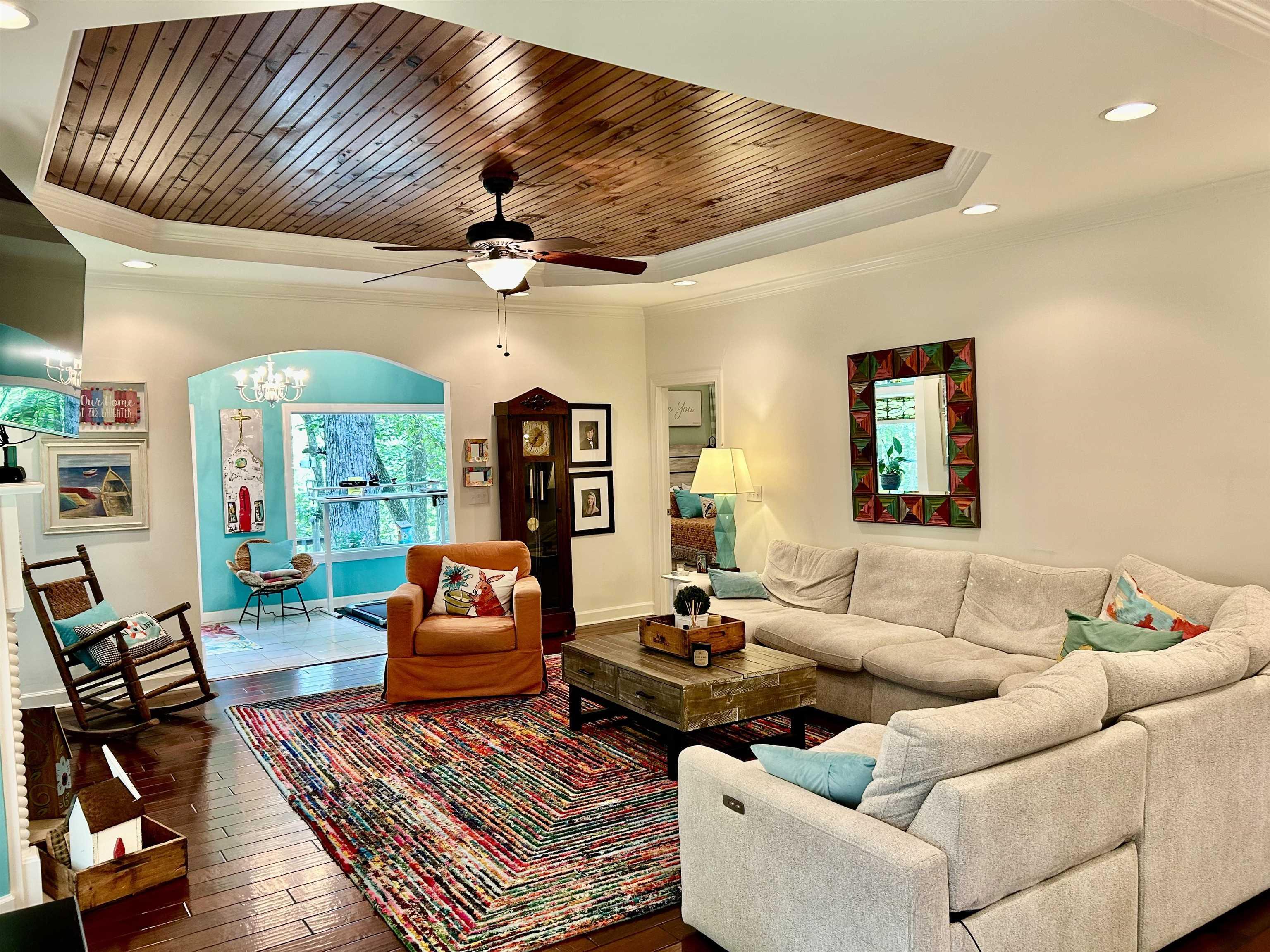 Image 3: Living room featuring a tray ceiling, crown molding, hardwood / wood-style floors, wooden ceiling, and ceiling fan