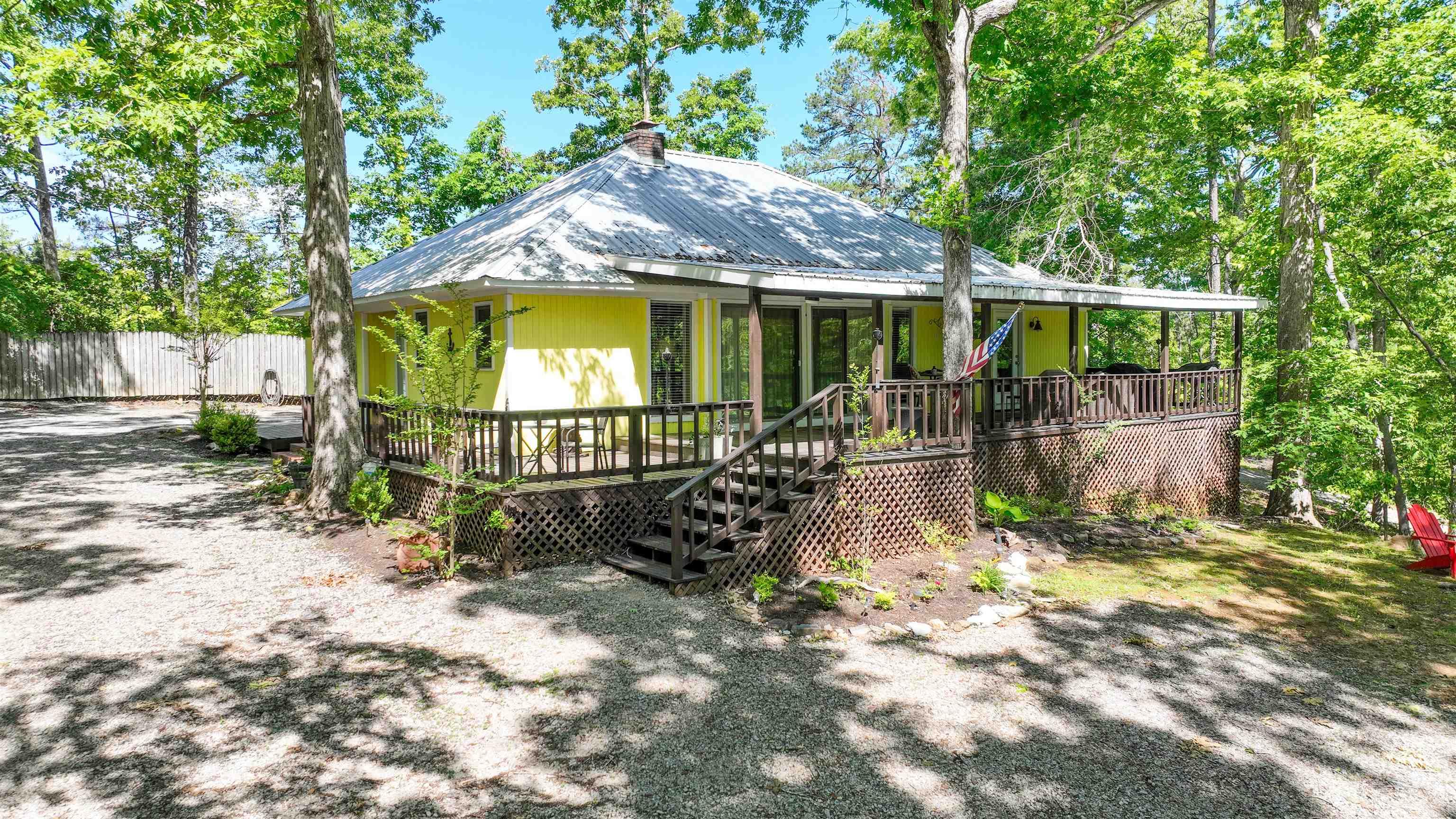 Image 1: Yellow-sided residence with an elevated wrap-around porch and a metal roof