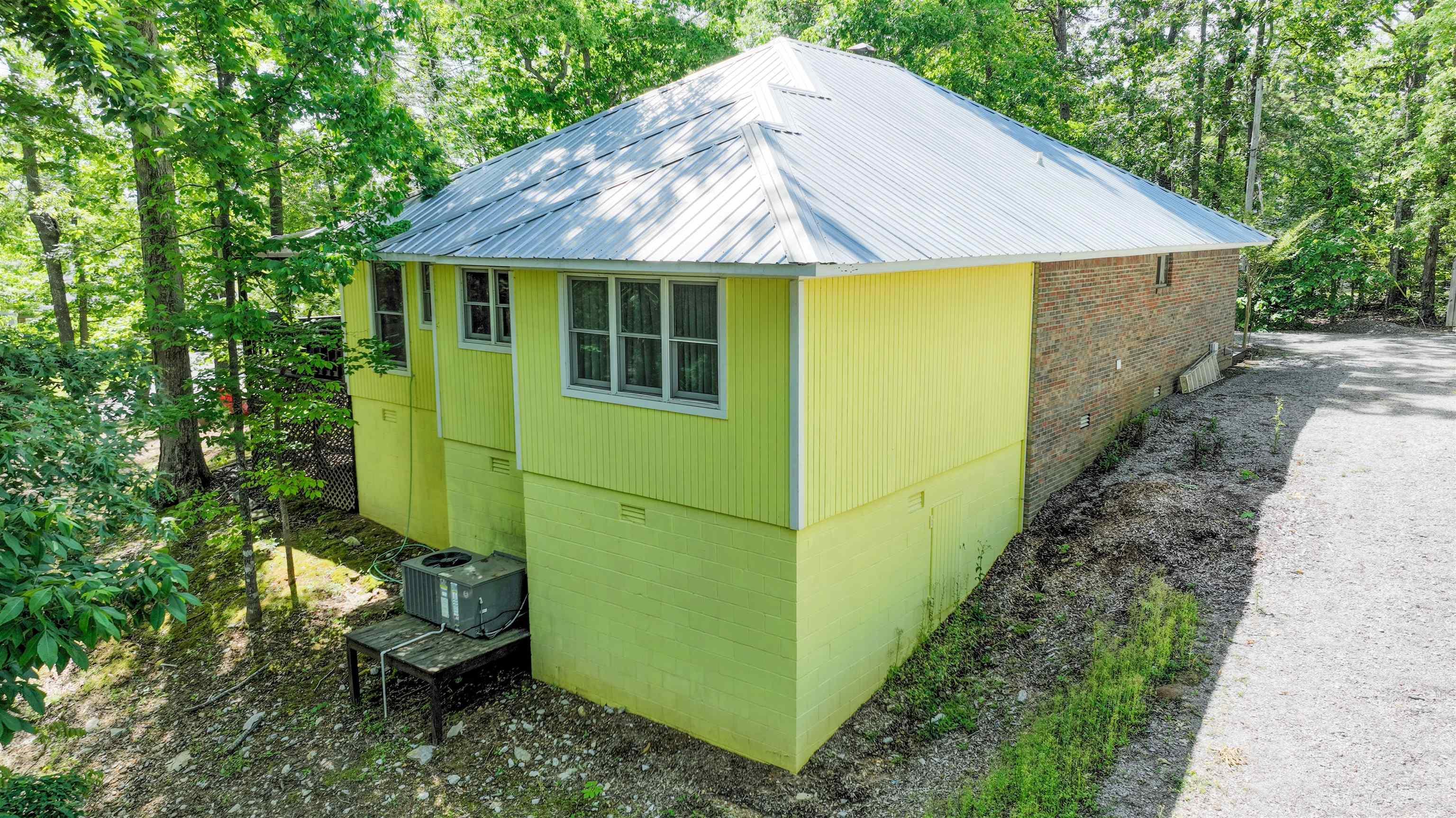 Image 2: Lime green siding and stacked stone exterior featuring a metal roof