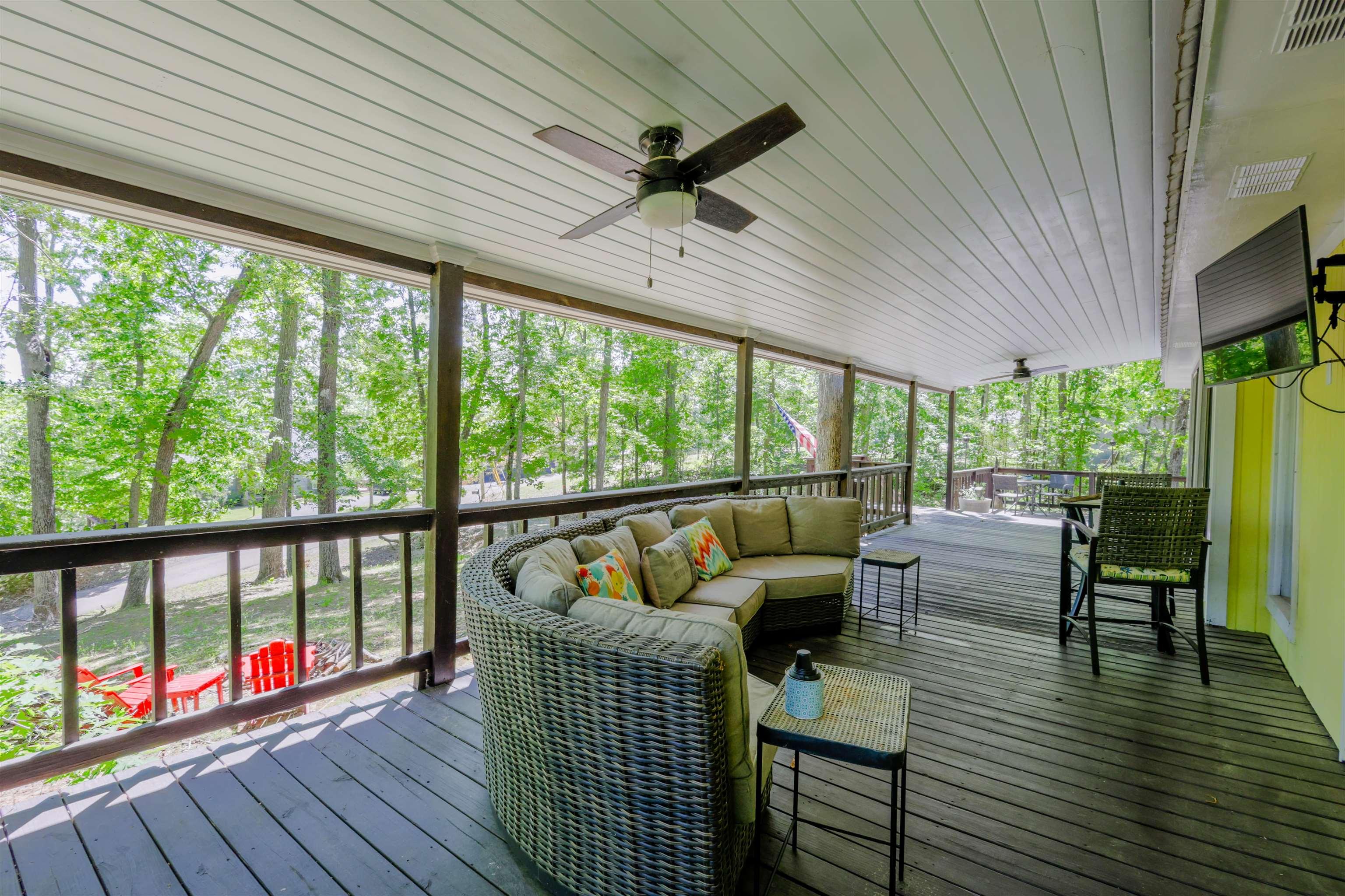 Image 4: Expansive covered deck featuring dark-stained wood flooring and white planked ceiling