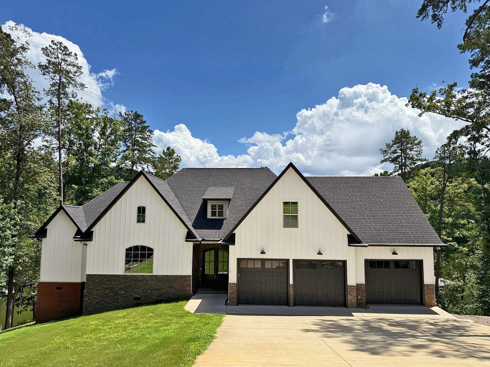 Image 1: Modern farmhouse style home with roof with shingles, driveway, a front lawn, an attached garage, and board and batten siding