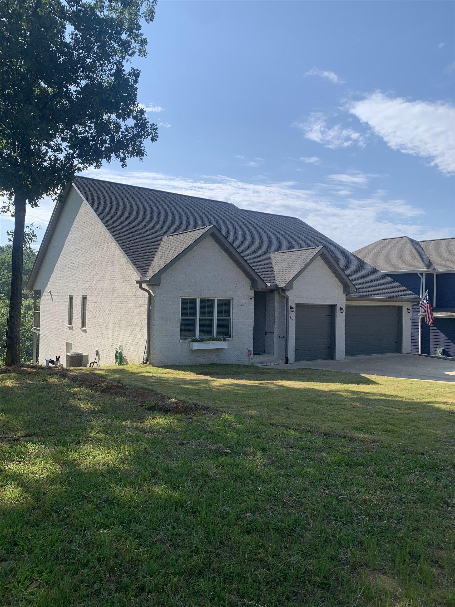 Image 2: Contemporary home exterior featuring a light gray brick facade, dark shingle roof, and a two-car garage
