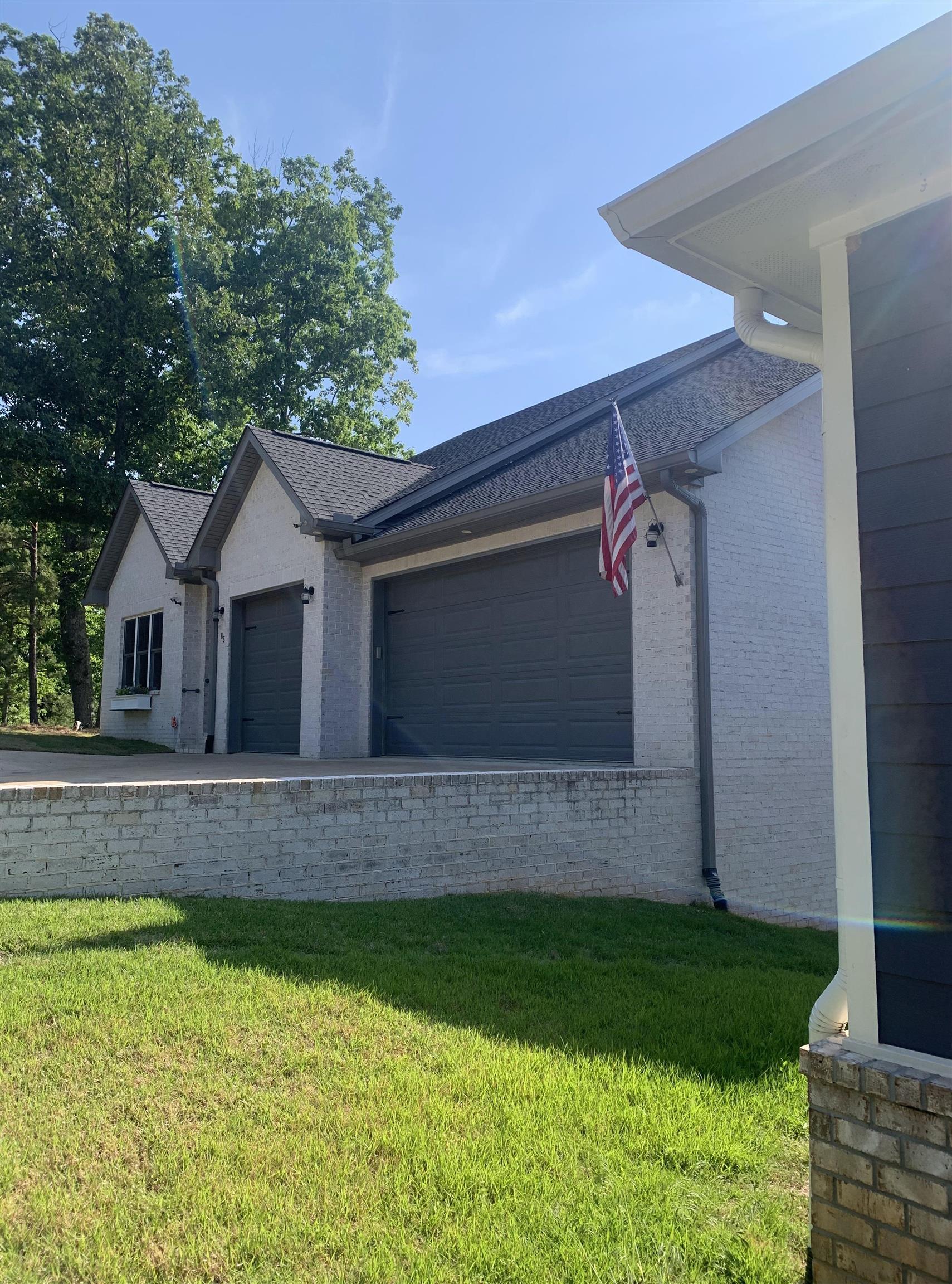 Image 3: Two-car garage with dark gray doors and a light-colored brick exterior