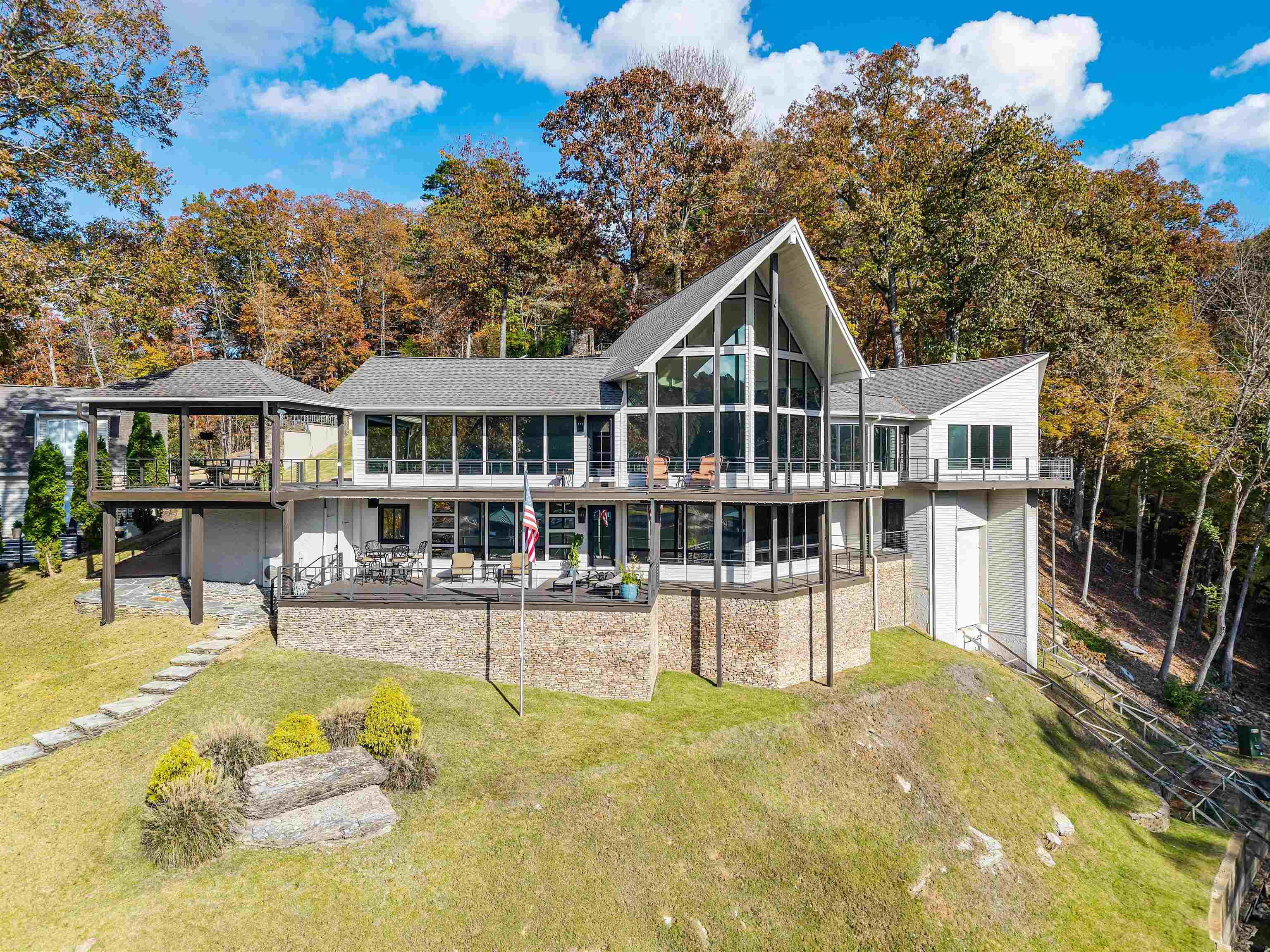 Image 2: Rear view of property featuring view of wooded area, a lawn, a wooden deck, and a patio