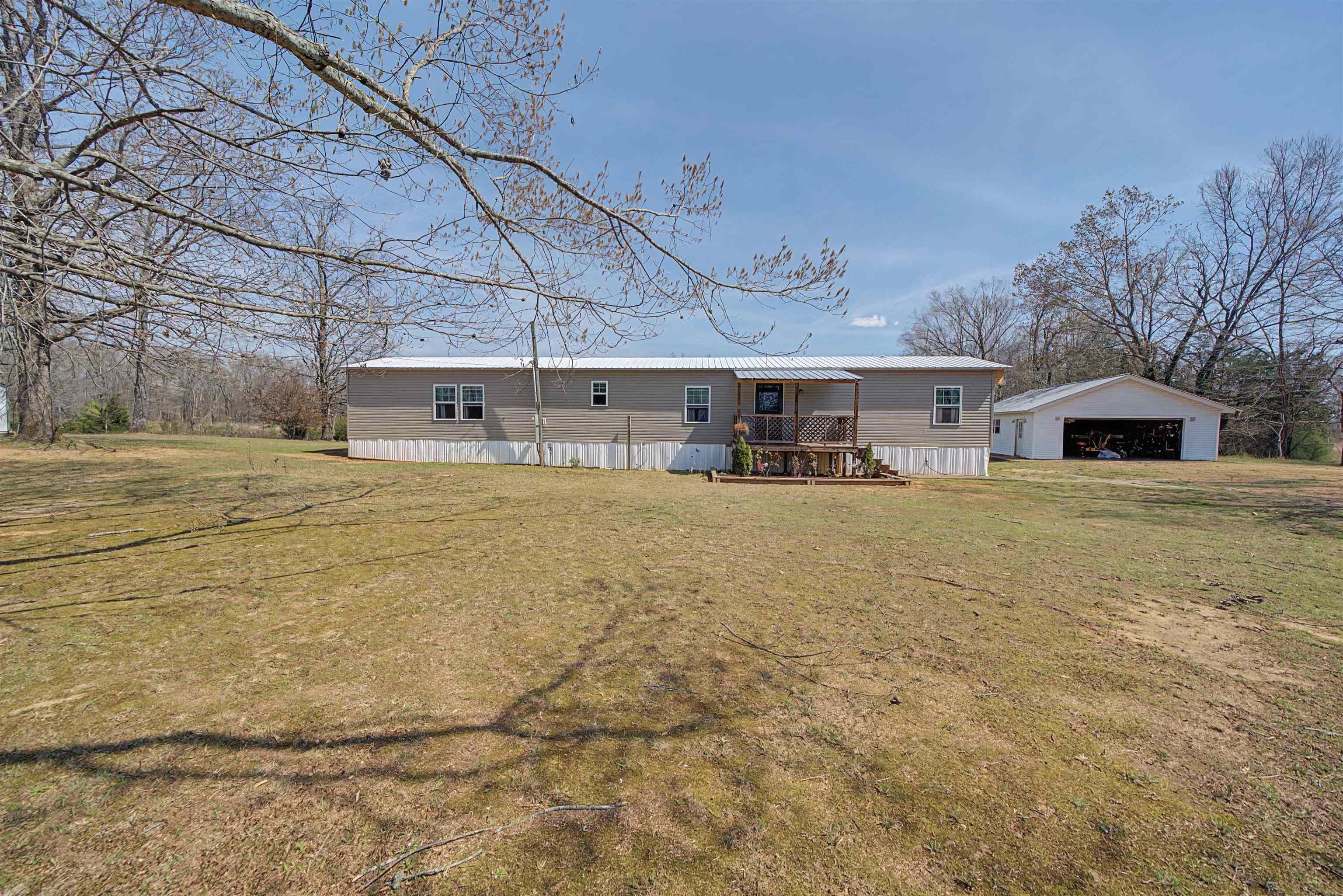 Image 2: View of front of house featuring an outbuilding, a front lawn, a detached garage, and a wooden deck