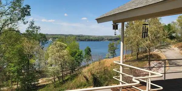 Image 2: Expansive wood-finish deck with a white railing system, featuring a partial roof overhang