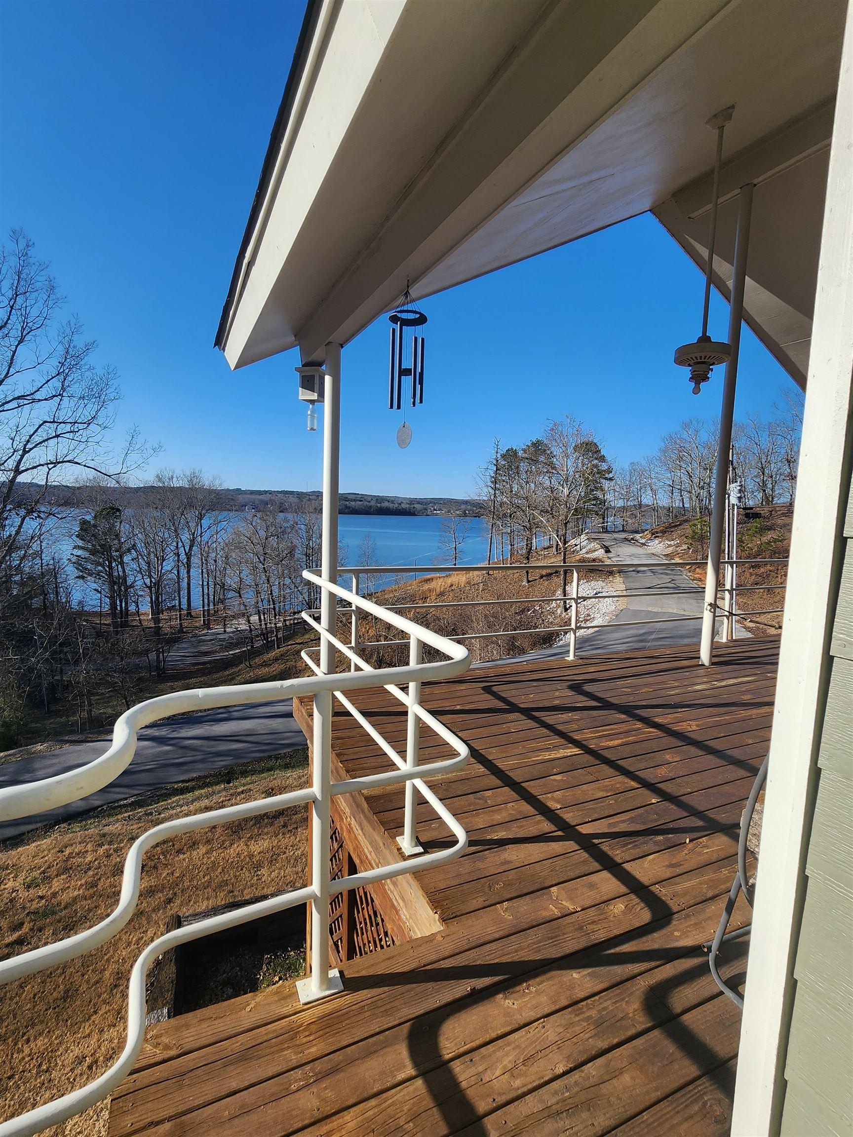 Image 3: Expansive wood-finish deck with white metal railings, offering serene water and tree-lined shoreline