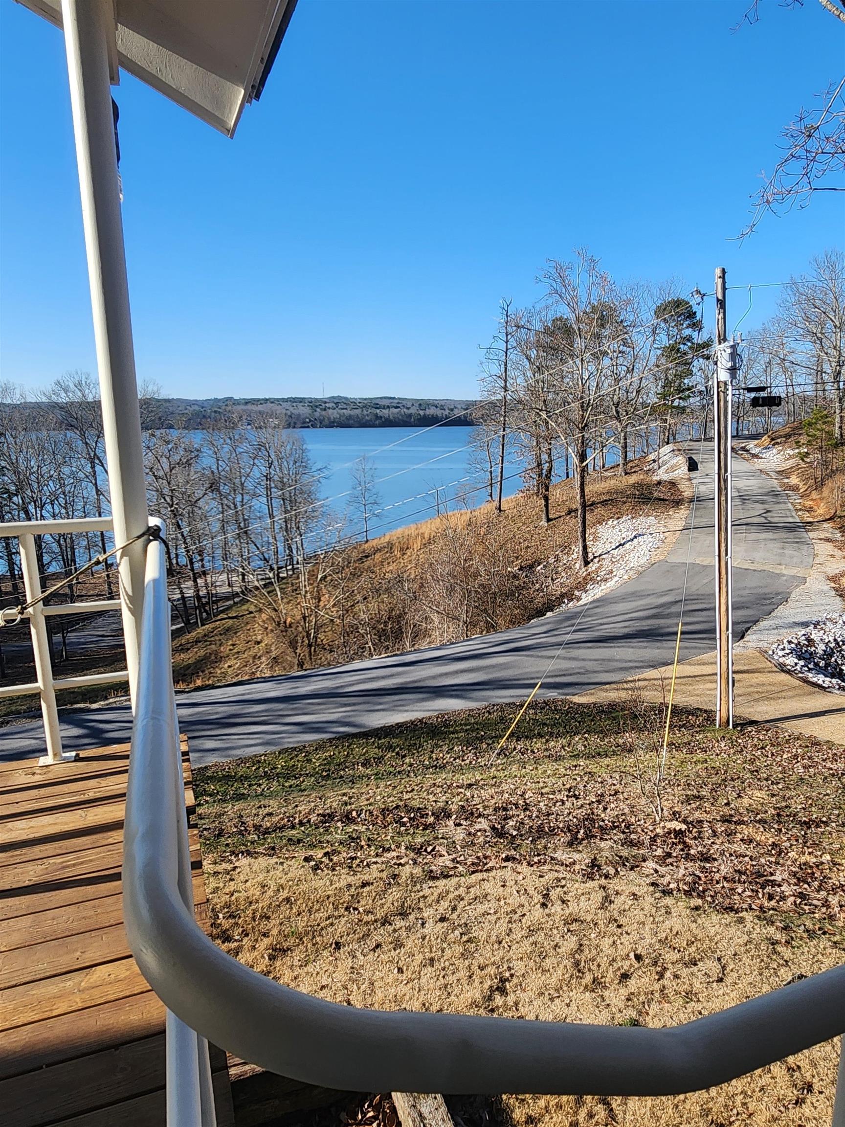 Image 4: Waterfront setting featuring expansive water, distant tree-lined shores, and a paved road