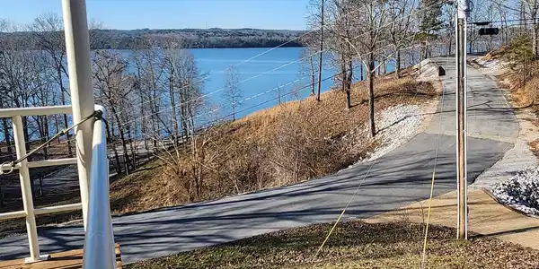 Image 4: Waterfront setting featuring expansive water, distant tree-lined shores, and a paved road