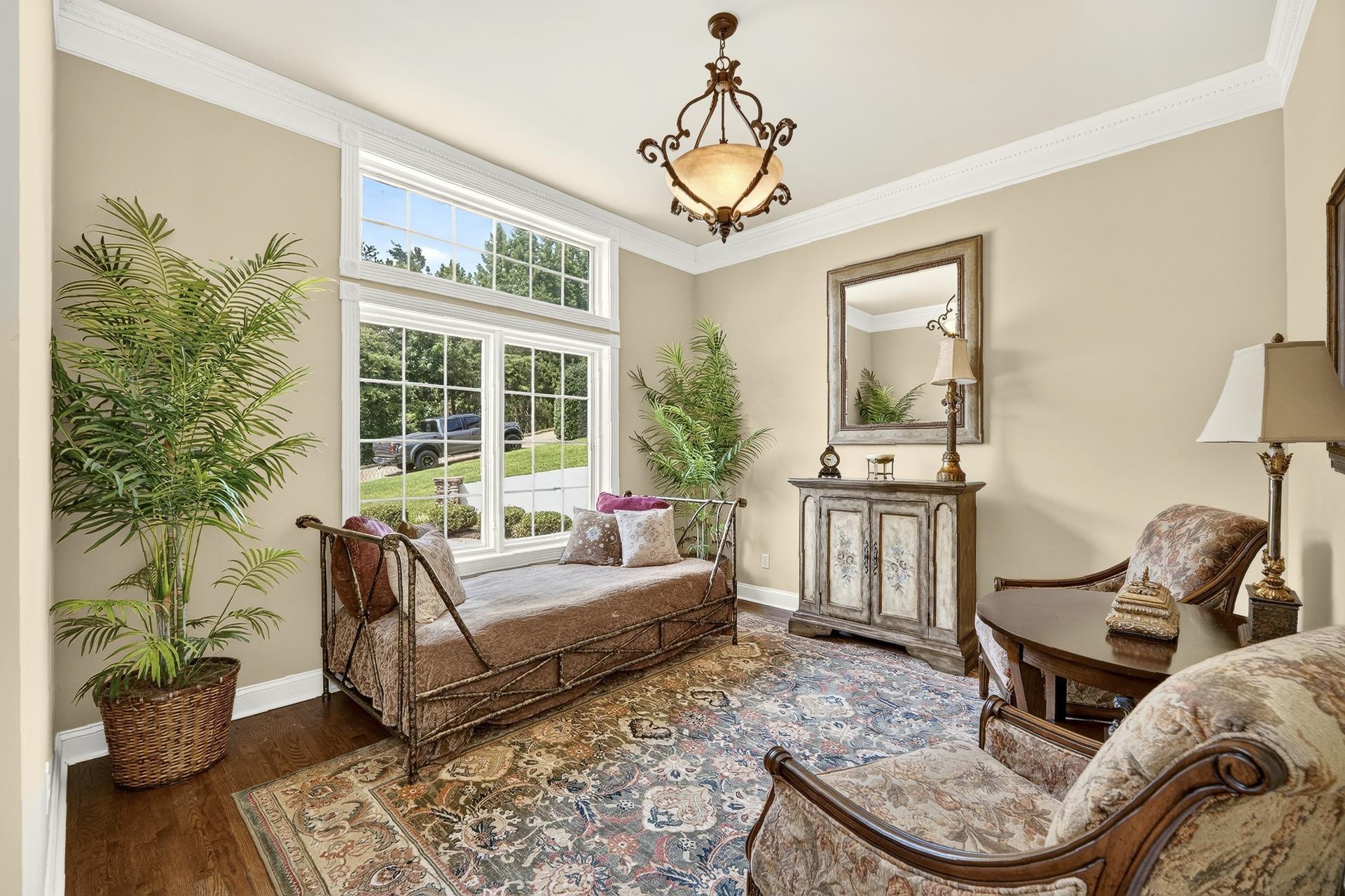 Image 4: Hardwood flooring complements a spacious room featuring large multi-pane windows and a detailed crown molding