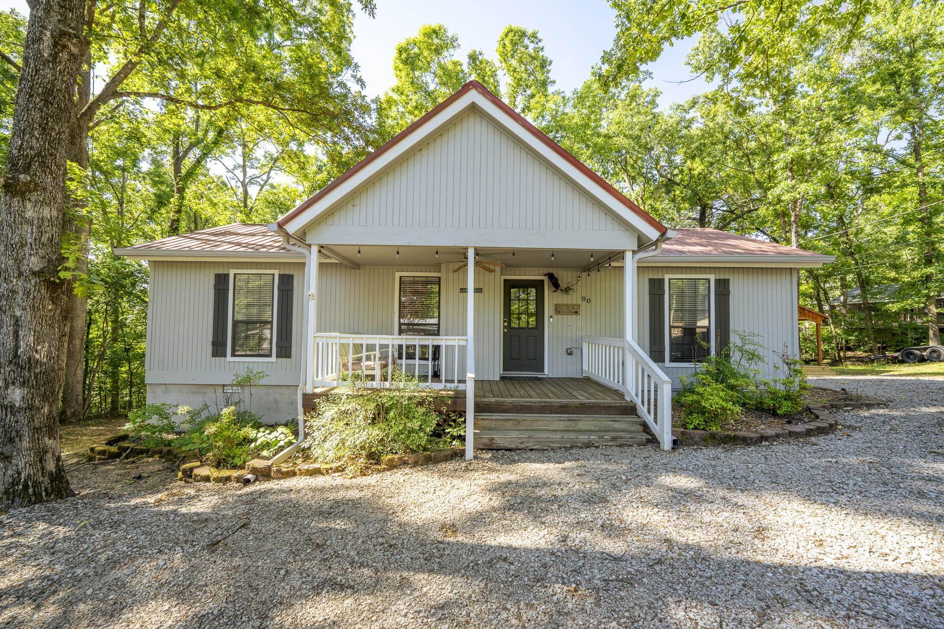 Image 1: Ranch-style exterior featuring light-colored siding, dark shutters, and a covered front porch with white railings